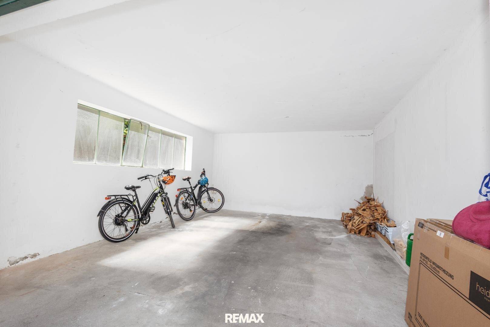 Geräumige Garage mit Betonboden, Fenster und Abstellmöglichkeiten.