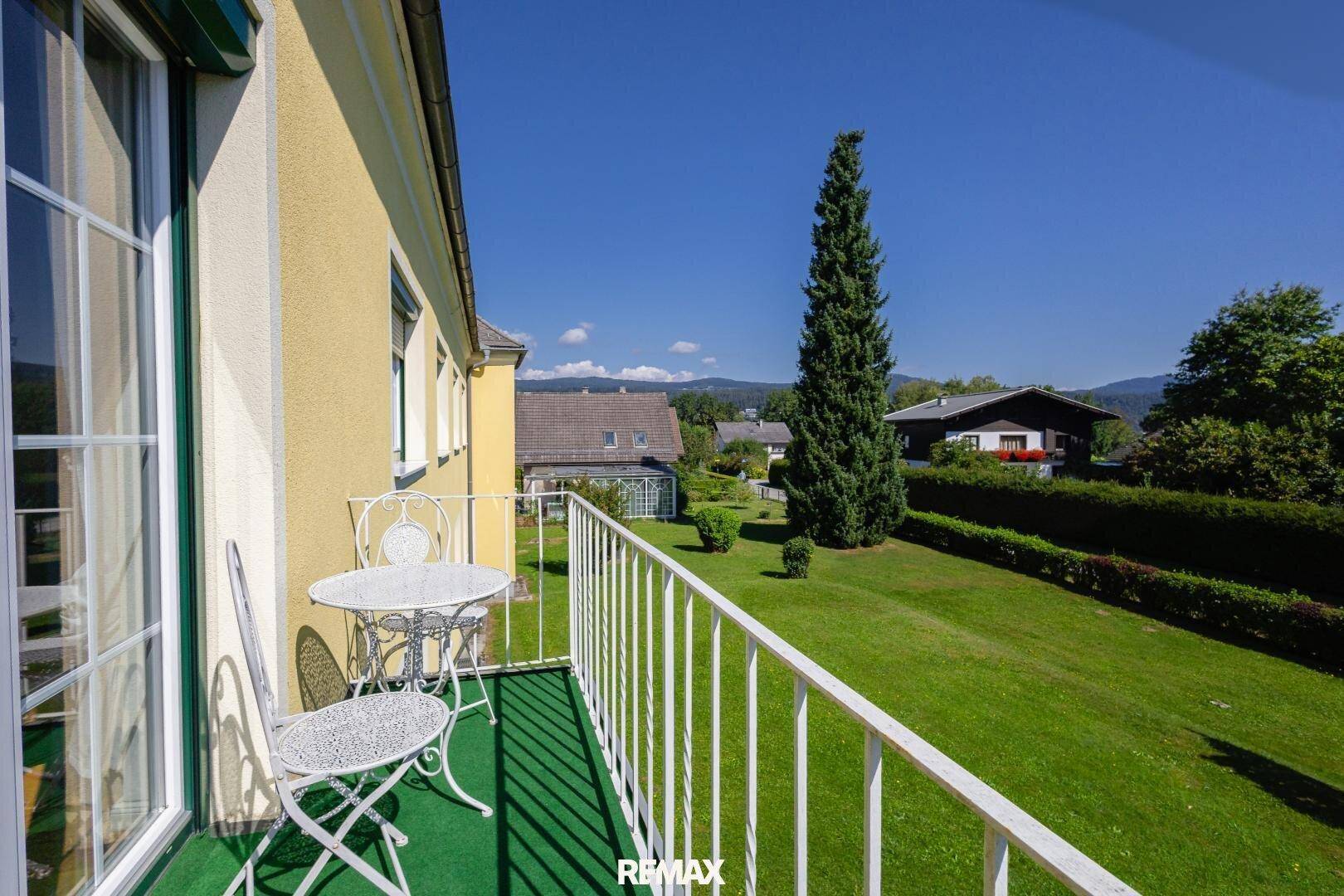 Kleiner Balkon mit Sitzgelegenheiten und weitem Blick über grüne Gärten und die Umgebung.