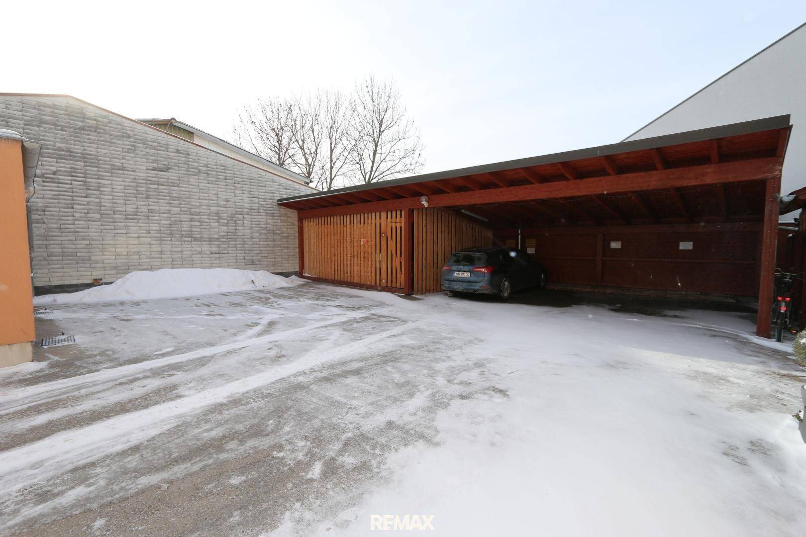 Innenansicht des Holzcarports mit einem geparkten Auto und seitlicher Holzverkleidung.