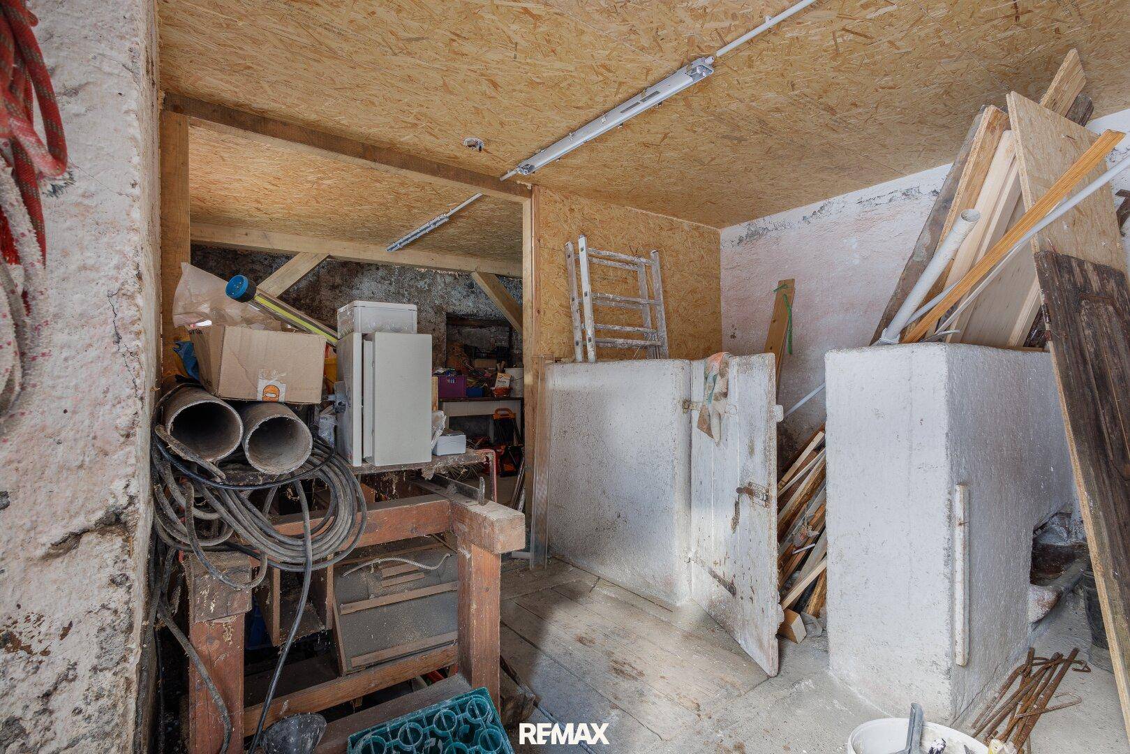 Unaufgeräumter Lagerraum oder Werkstatt mit sichtbaren Holzbalken und verschiedenen Materialien.