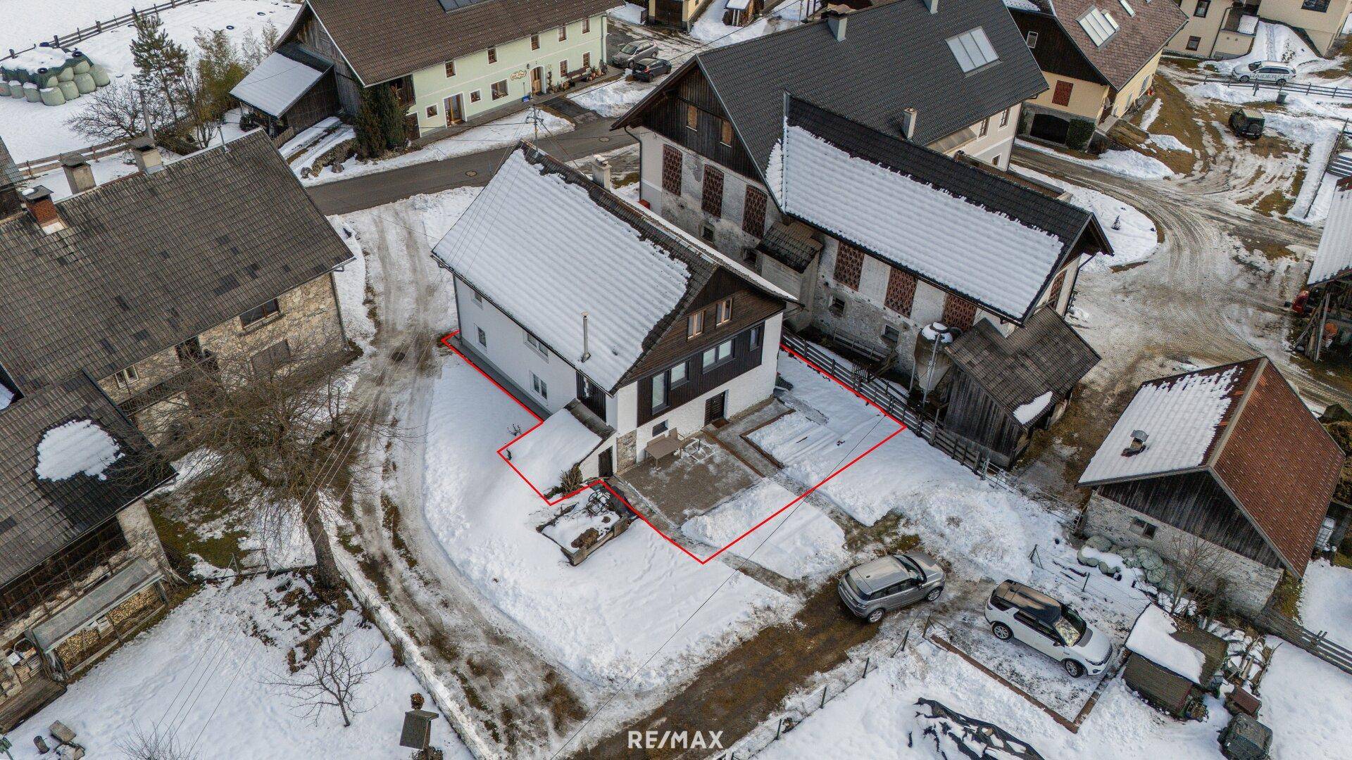 Luftaufnahme des Hauses und des Grundstücks mit roter Umrandung im Winter.