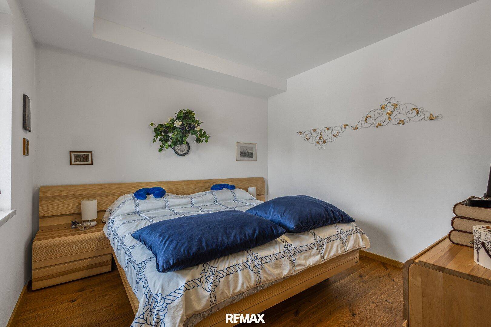 Helles Schlafzimmer mit Holzbett, Nachttischen und weiß gestrichenen Wänden.