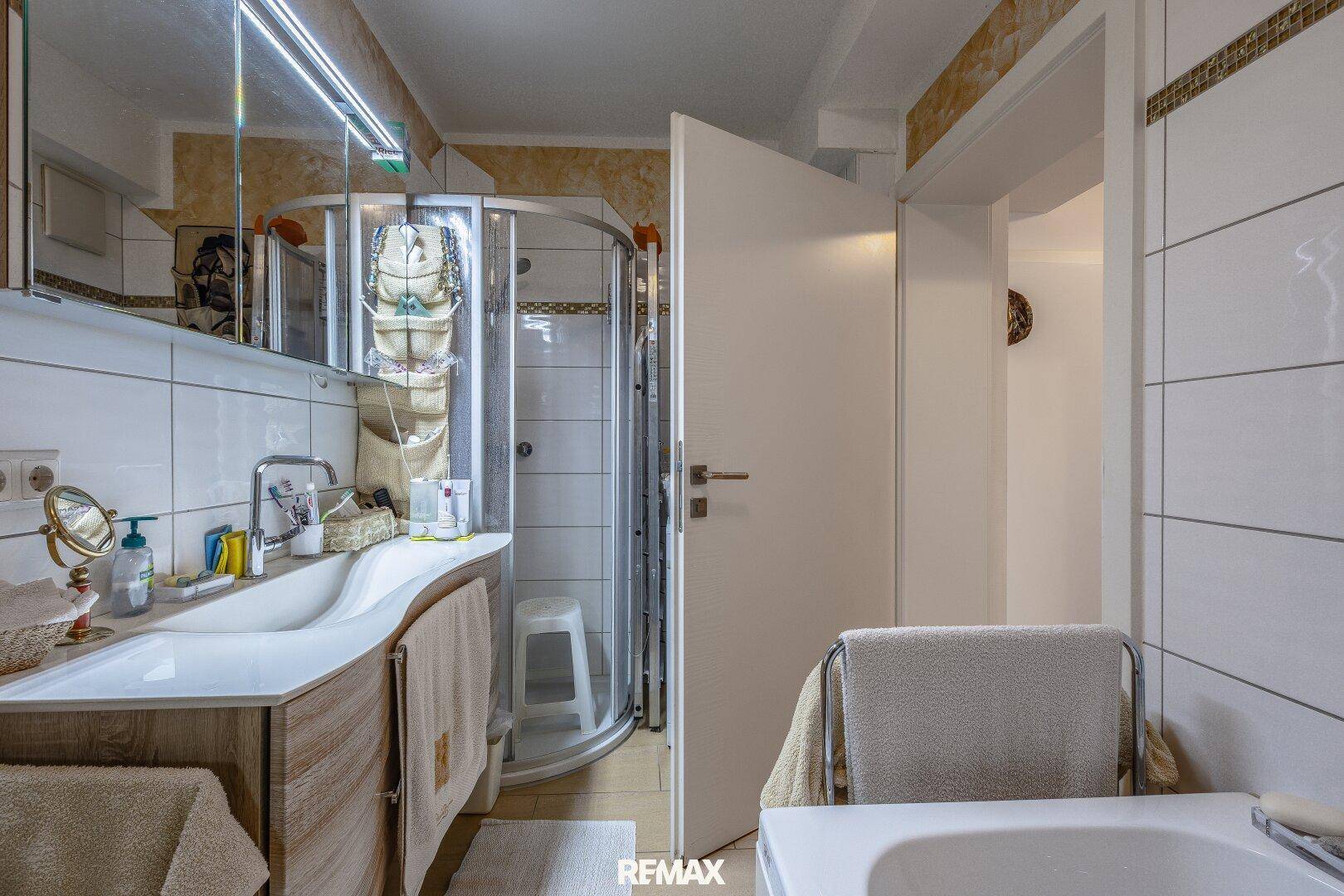 Badezimmer mit Duschkabine, Waschbecken mit Unterschrank und Badewanne.