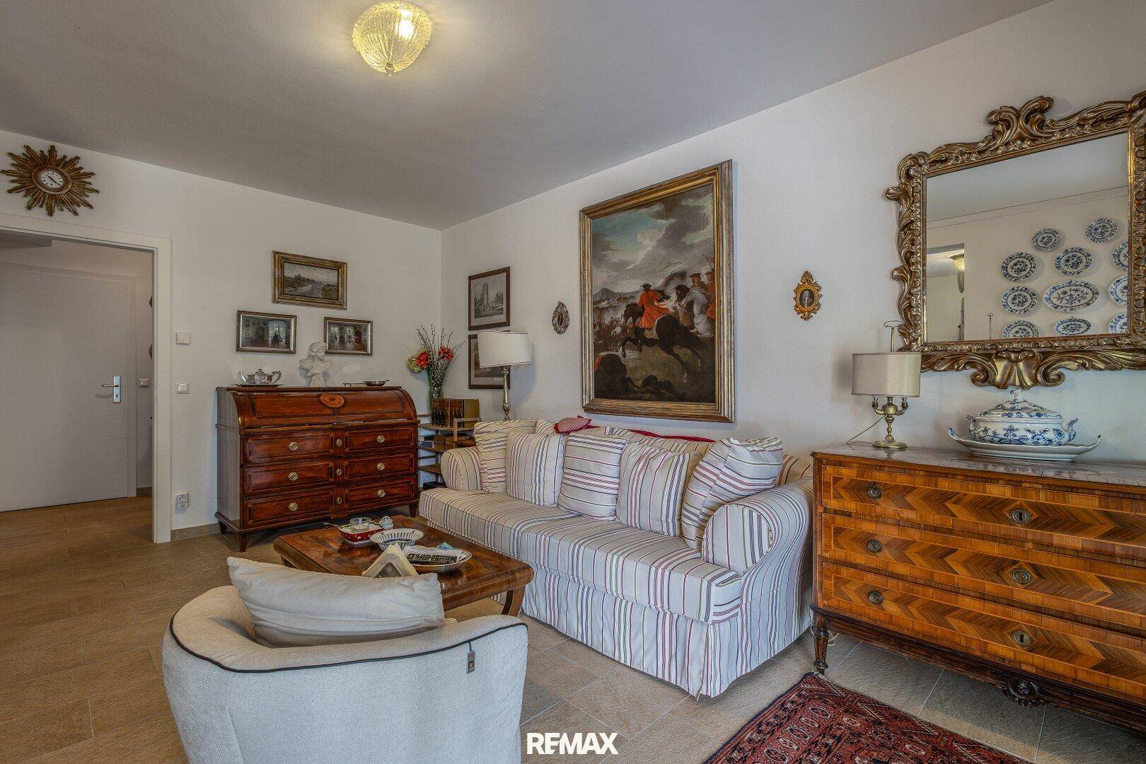 Wohnzimmer mit bequemen Sofas, Fliesenboden und einem dekorativen Spiegel.
