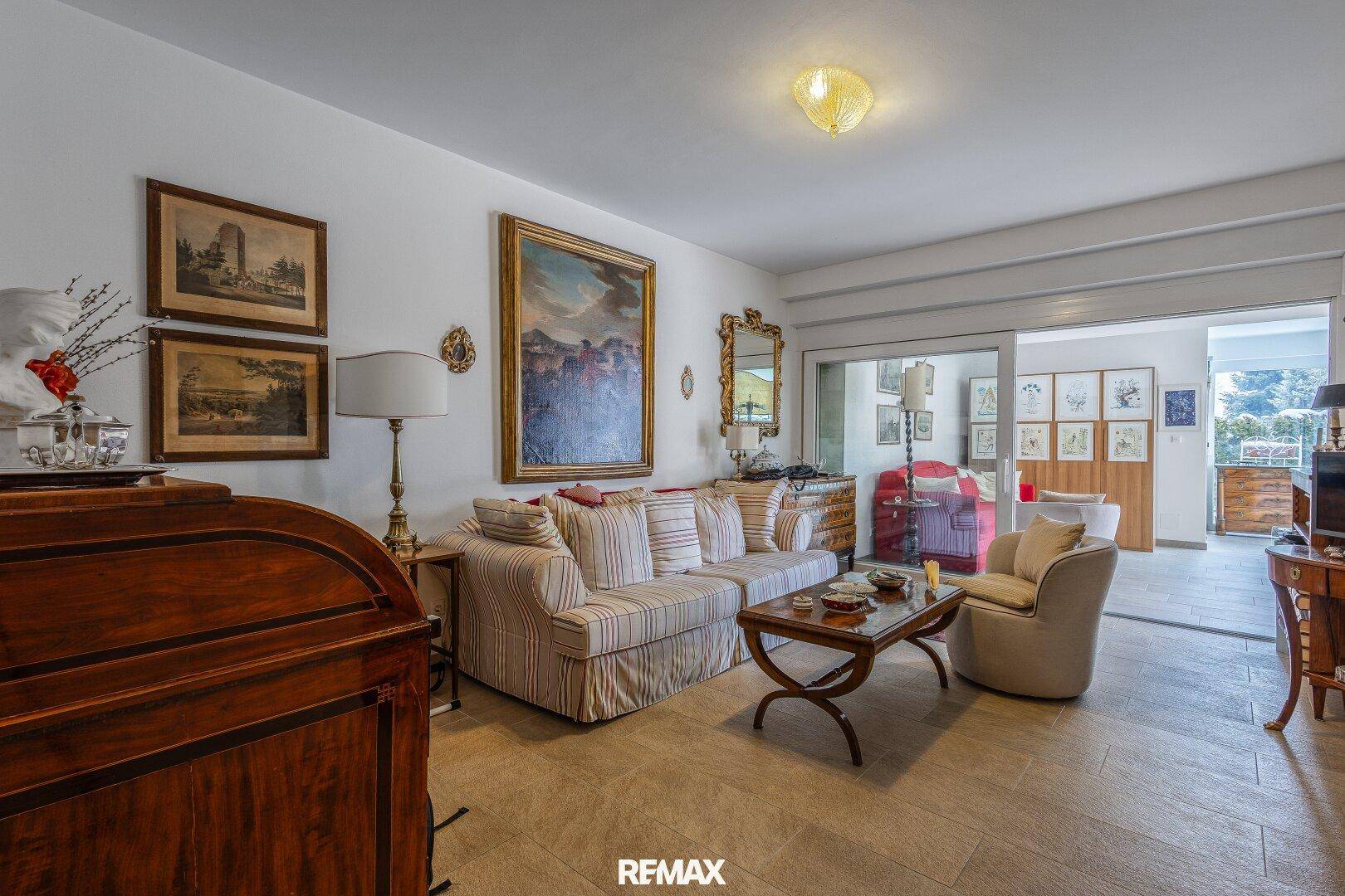 Gemütliches Wohnzimmer mit gestreiften Sofas, Fliesenboden und klassischer Dekoration.
