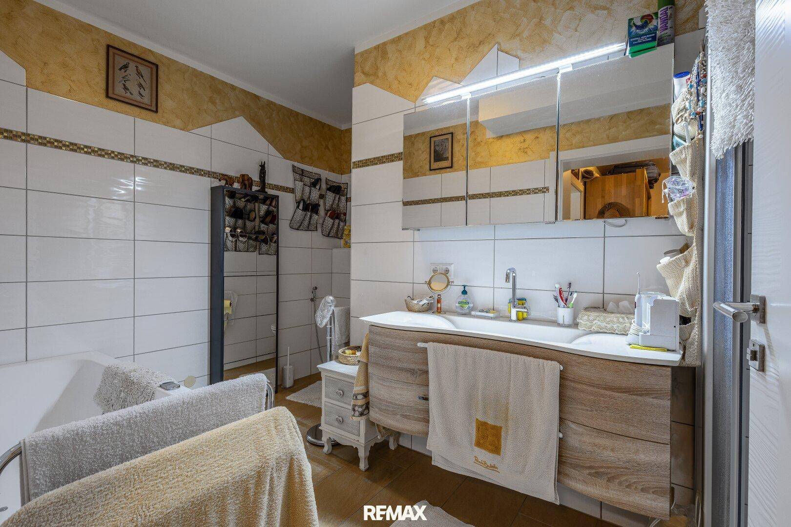 Geräumiges Badezimmer mit Doppelwaschbecken, Badewanne und weißen Fliesen.