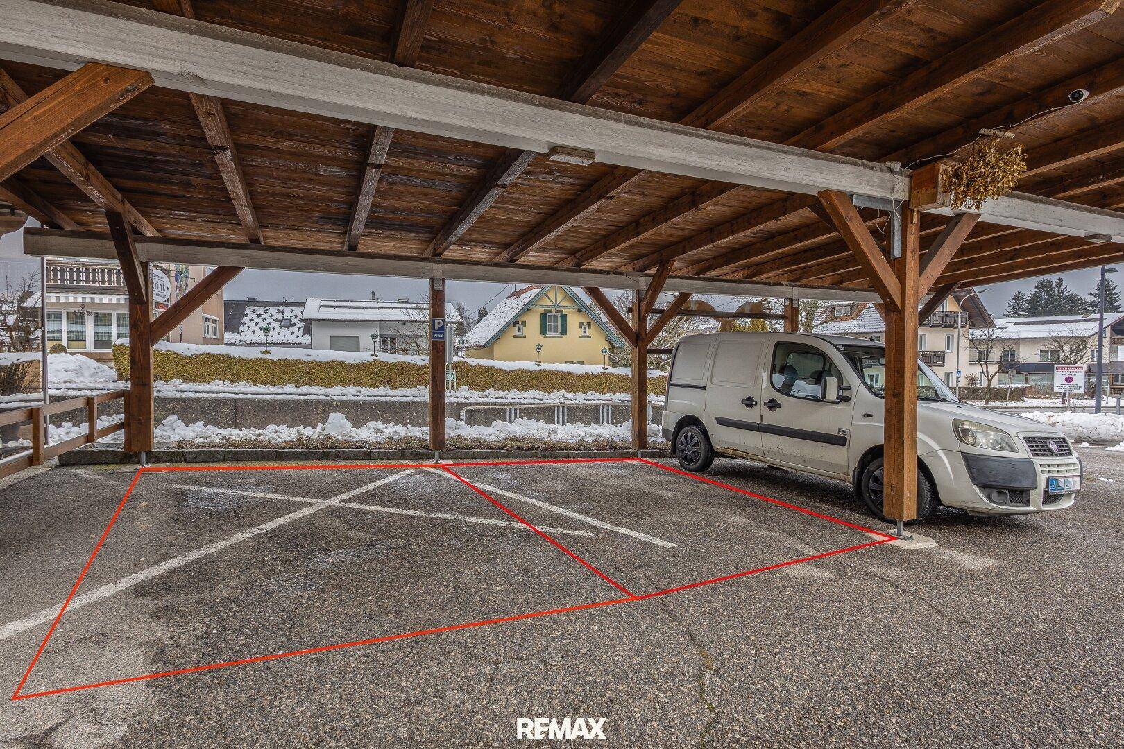 Überdachter Carport mit einem geparkten Lieferwagen und verschneiter Umgebung.