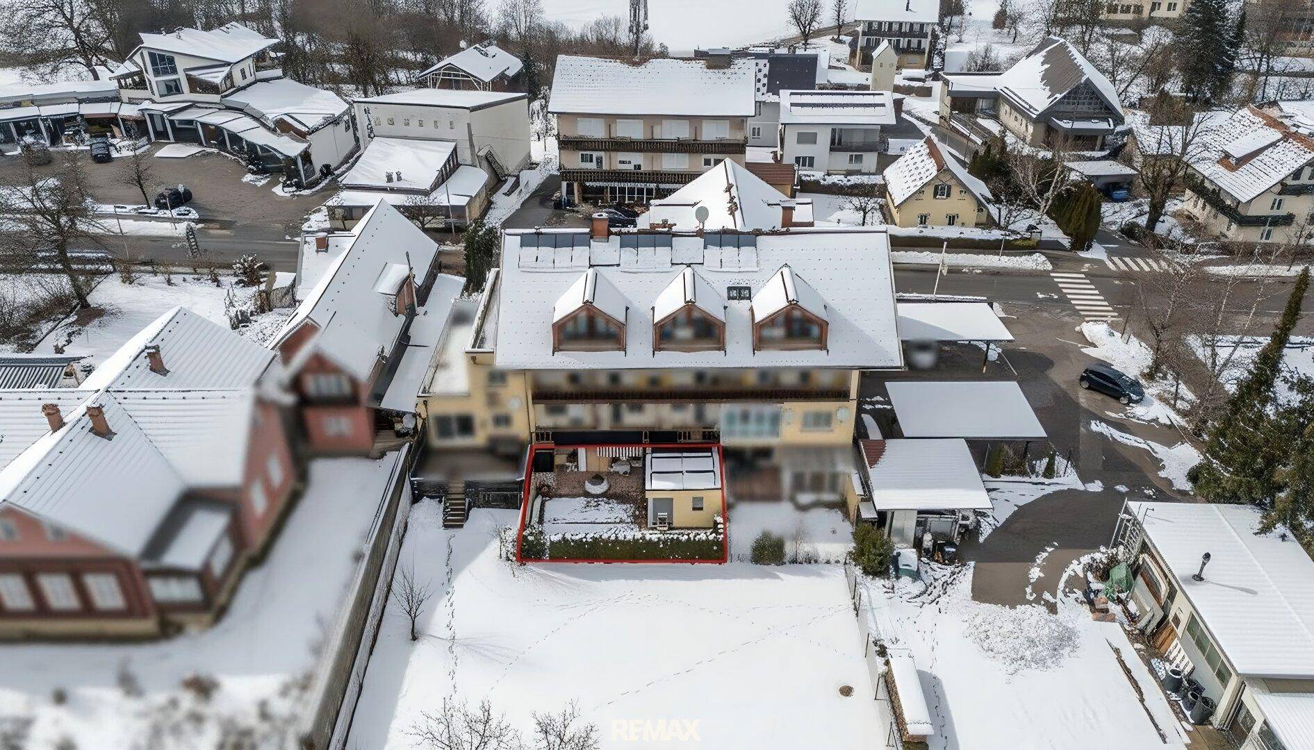 Luftaufnahme einer verschneiten Wohngegend mit Häusern und dem markierten Grundstück.