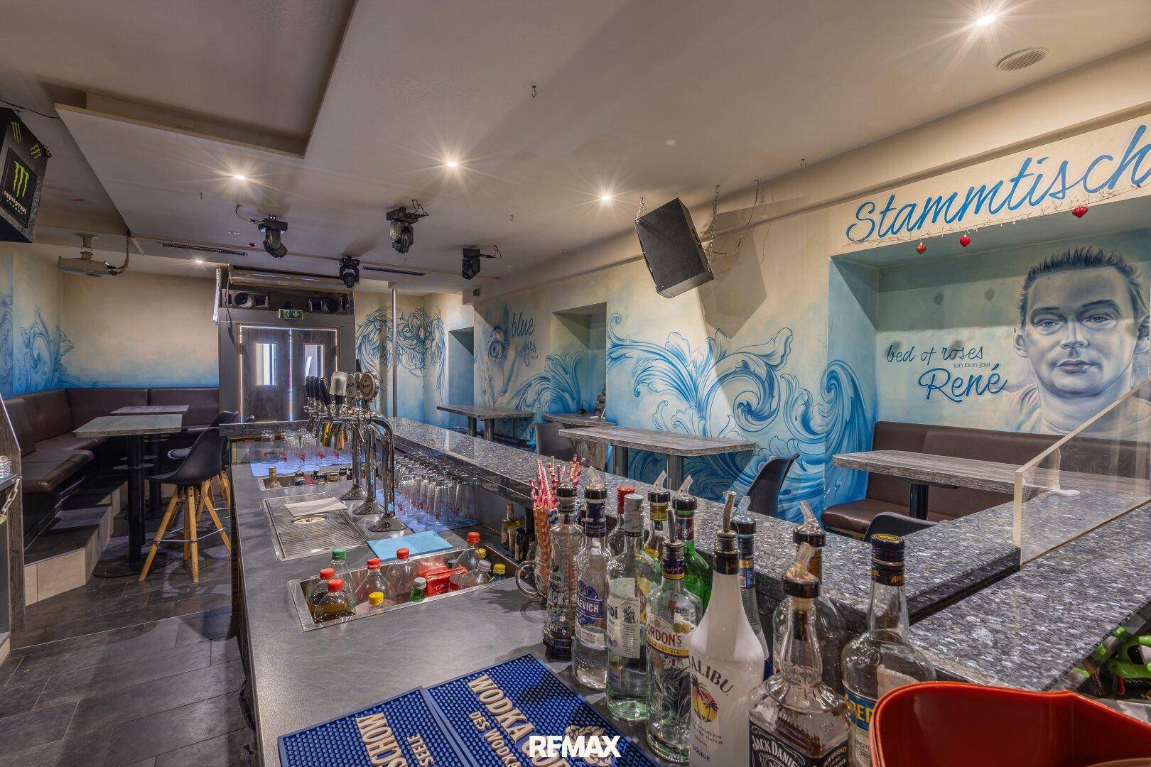 Gut ausgestattete Bar mit Getränken, Theke und Sitzbänken, ideal für Unterhaltung.