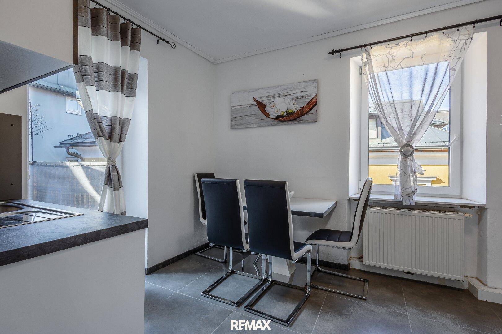 Heller Essbereich in der Küche mit modernem Tisch und Stühlen am Fenster.