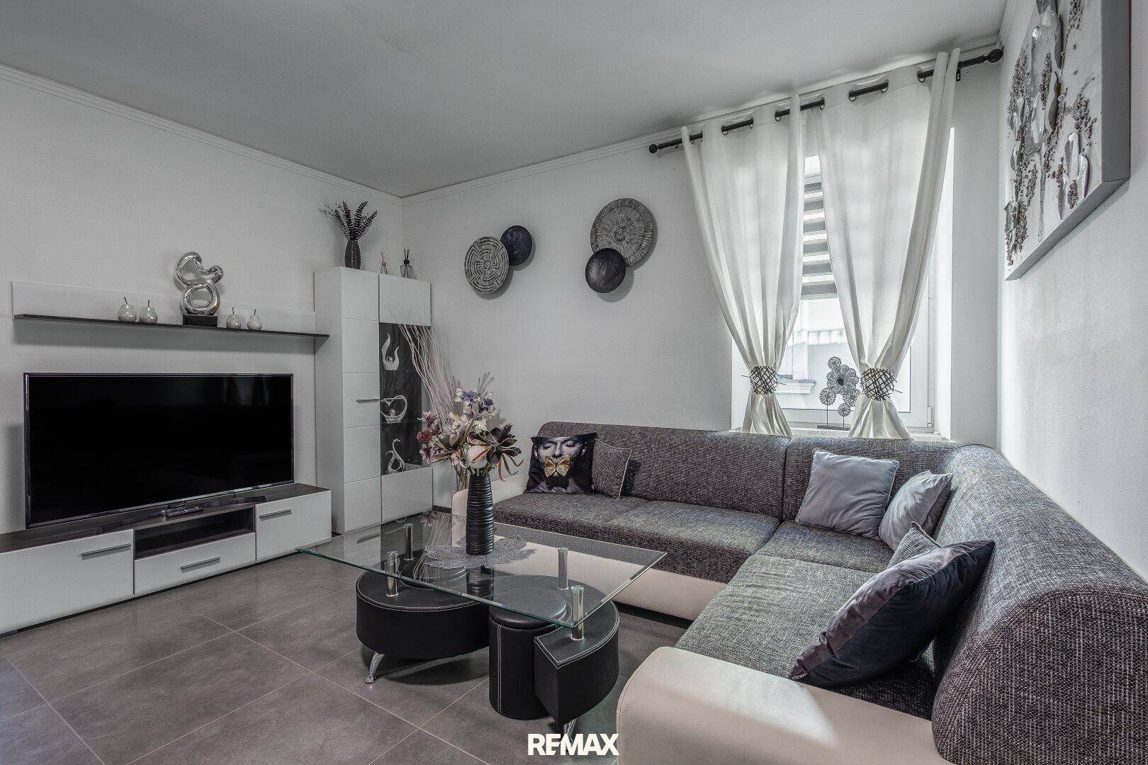 Modernes Wohnzimmer mit großem Ecksofa, Fliesenboden und stilvoller Dekoration.