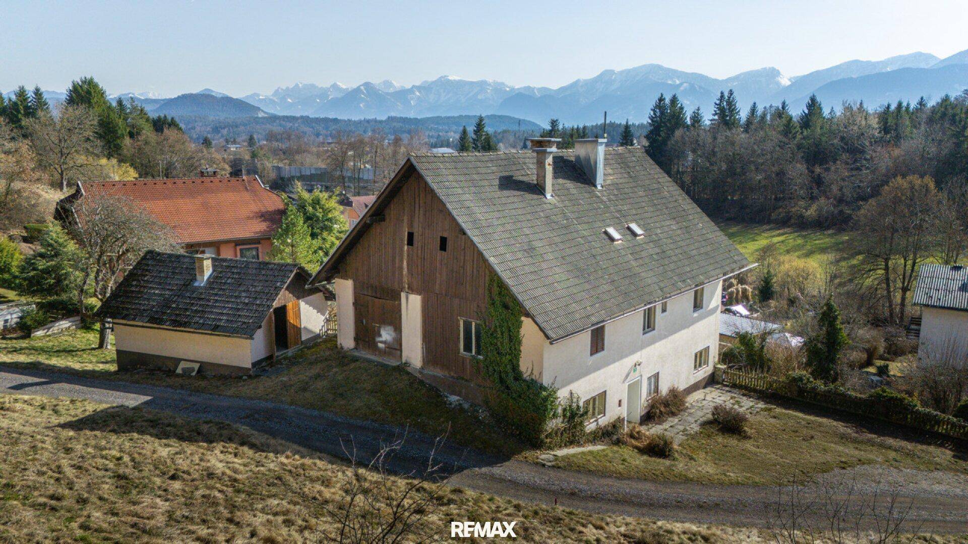 Rückansicht des Hauses mit Holzelementen an der Fassade und einem weiten Blick auf die Berge.