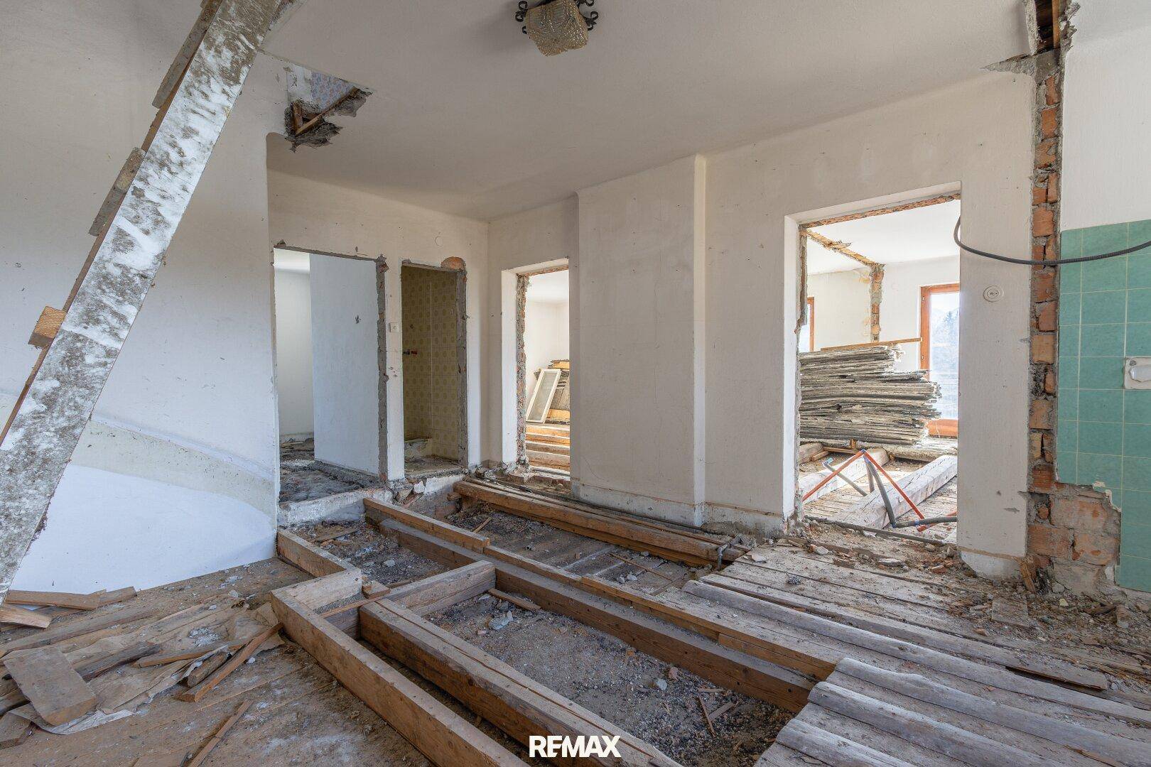 Raum in Renovierung mit freigelegten Bodenbalken und Baumaterialien, bereit für den Umbau.