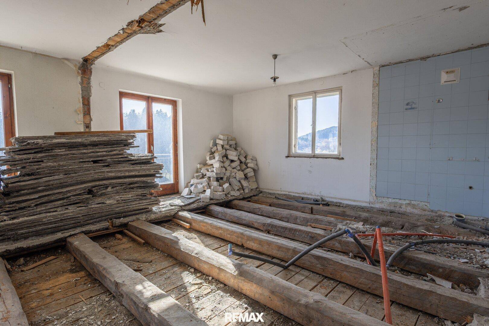 Raum in Sanierung mit teilweise gefliester Wand und Baumaterialien, bereit für die Neugestaltung.
