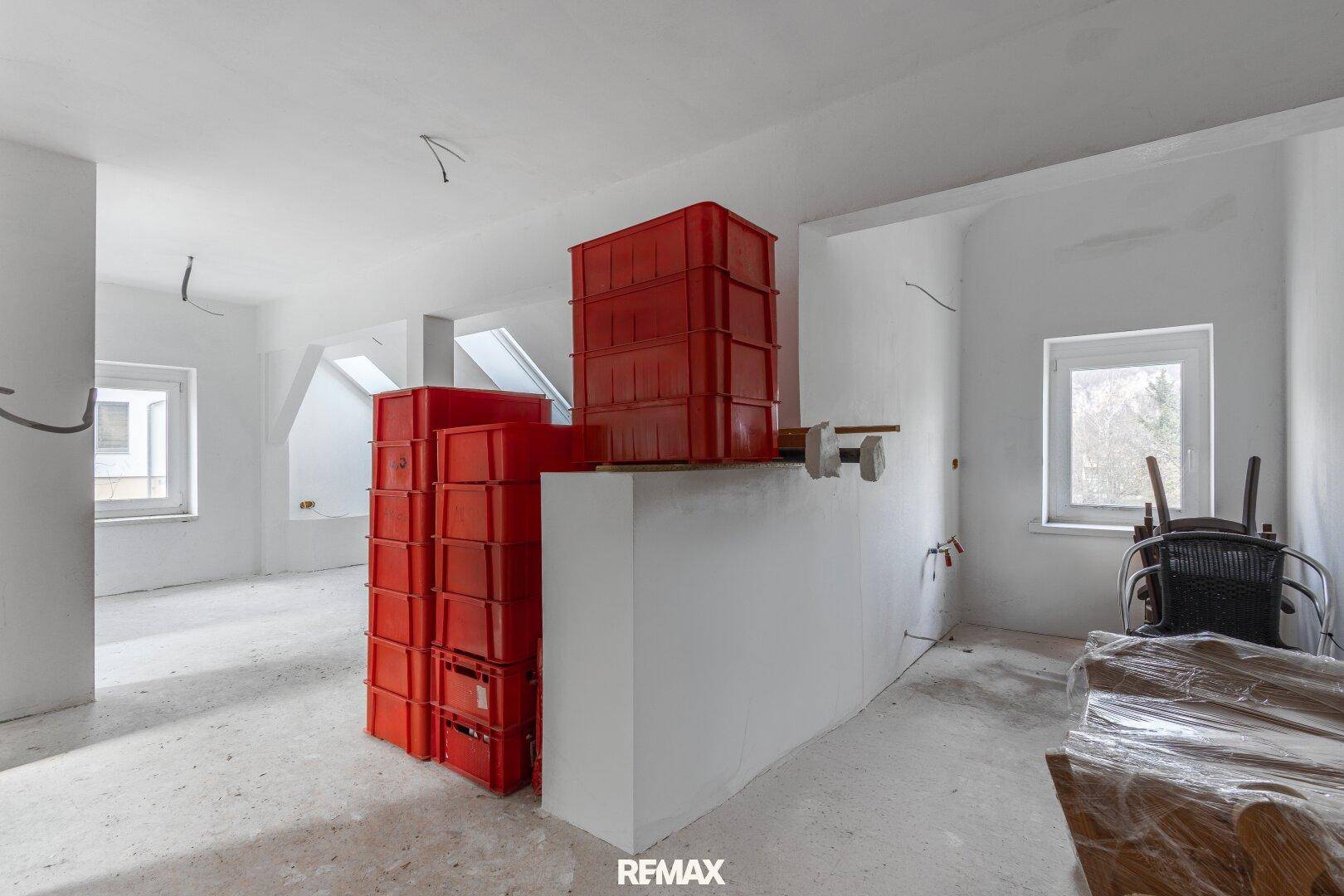 Geräumiger Dachbodenraum im Rohbau mit Fenstern und Lagerkisten.
