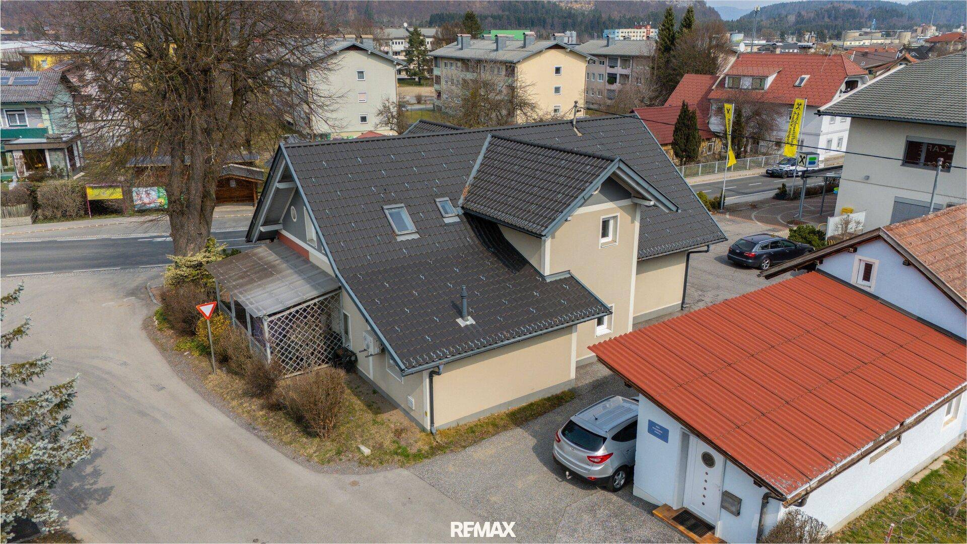 Rückansicht des gepflegten Gebäudes mit beiger Fassade, Parkplätzen und umliegender Wohnbebauung.