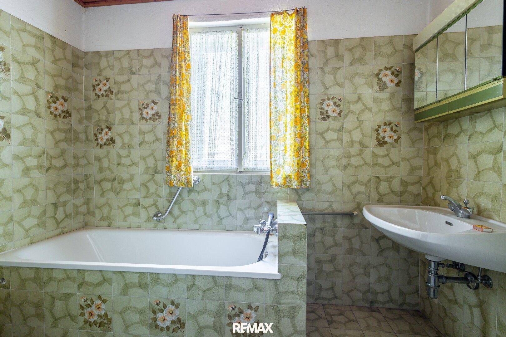 Badezimmer mit Badewanne, Waschbecken und gemusterten Fliesen im Vintage-Stil.