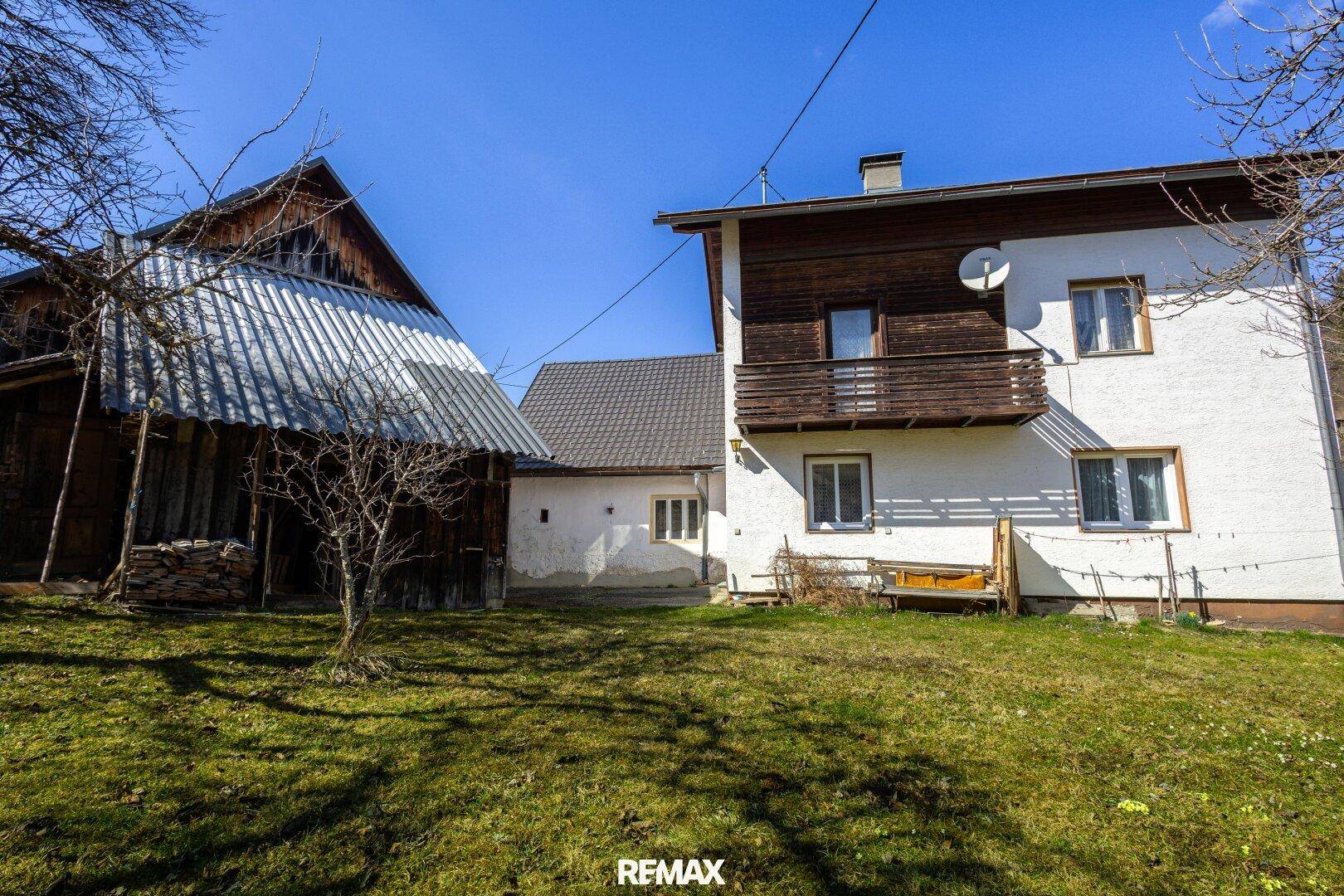 Rückseite des Hauses mit Balkon und großem Gartenbereich, umgeben von Natur.