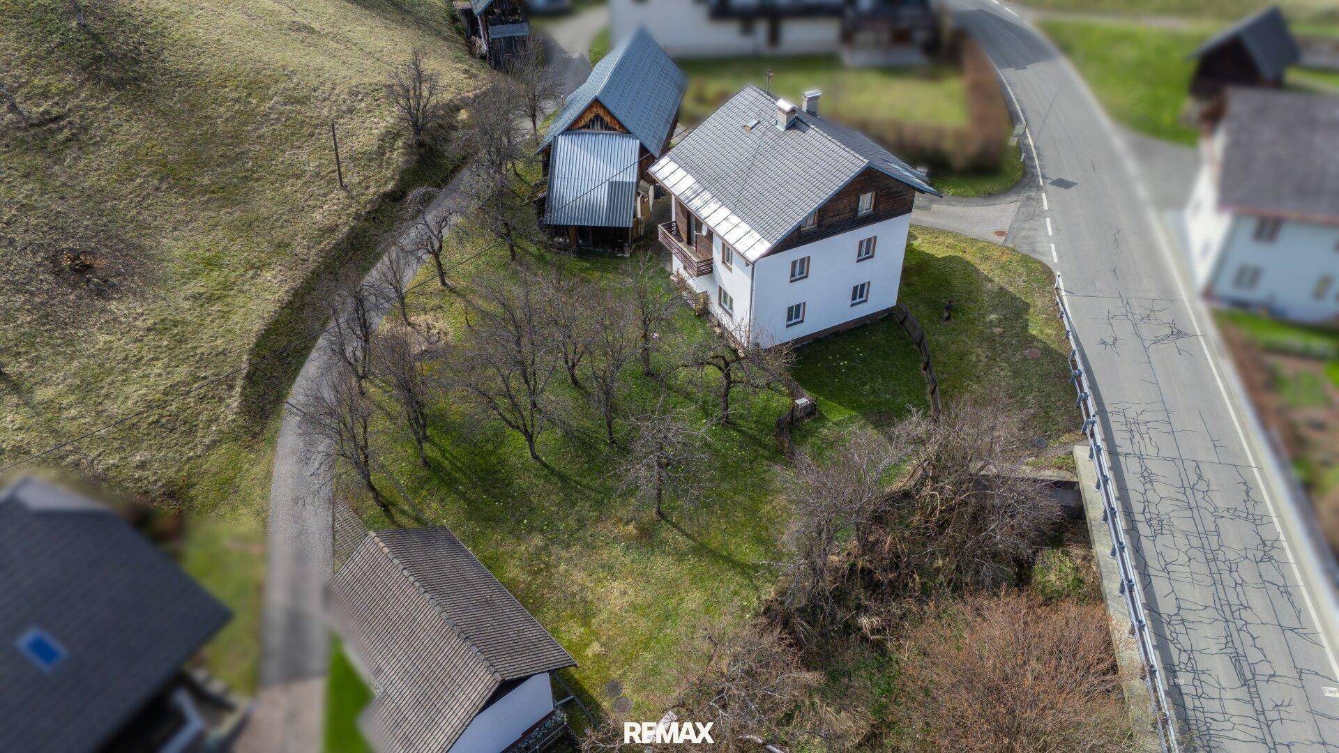 Vogelperspektive eines Wohnhauses mit Nebengebäude in einer hügeligen Landschaft.