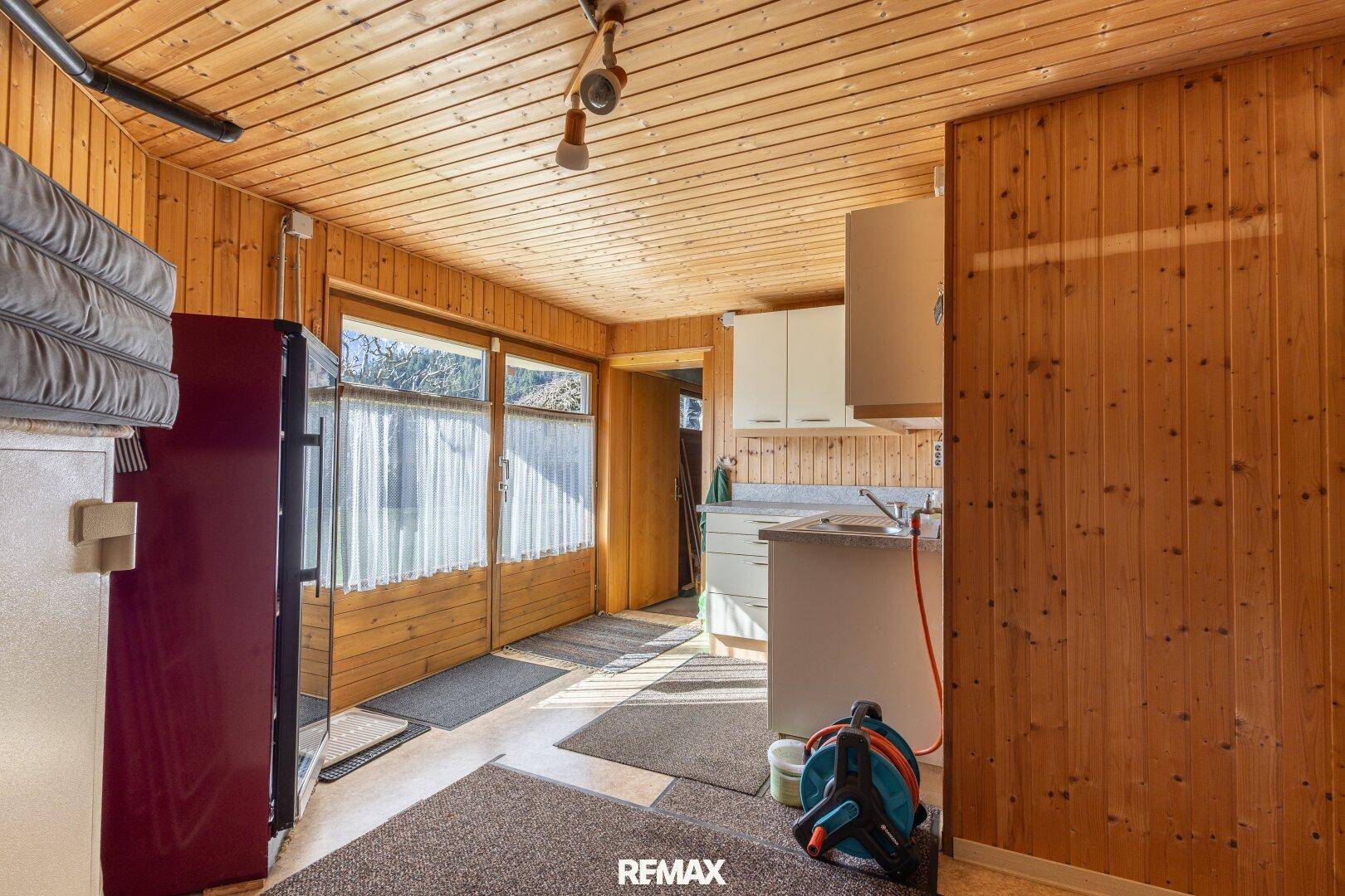 Hauswirtschaftsraum mit Holzvertäfelung, Spüle und Blick in den Garten.