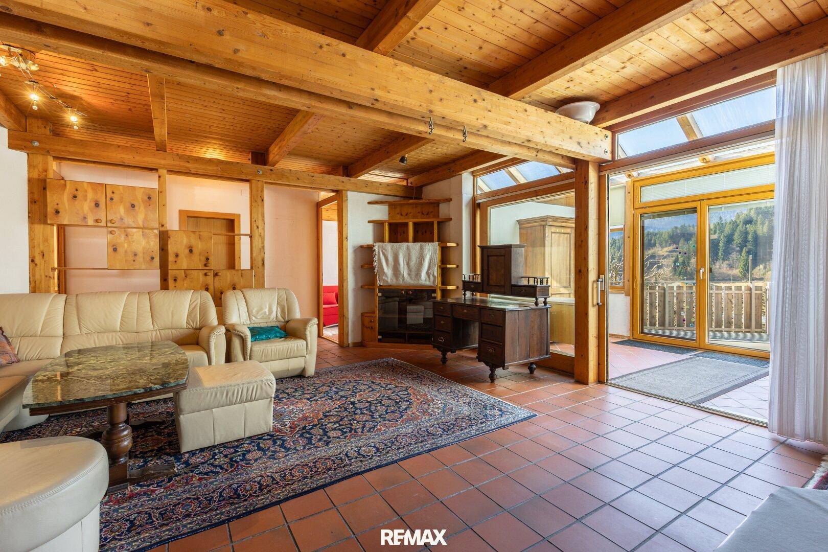 Helles Wohnzimmer mit Holzbalkendecke, Terrakottaboden und Zugang zu einem Balkon mit Aussicht.