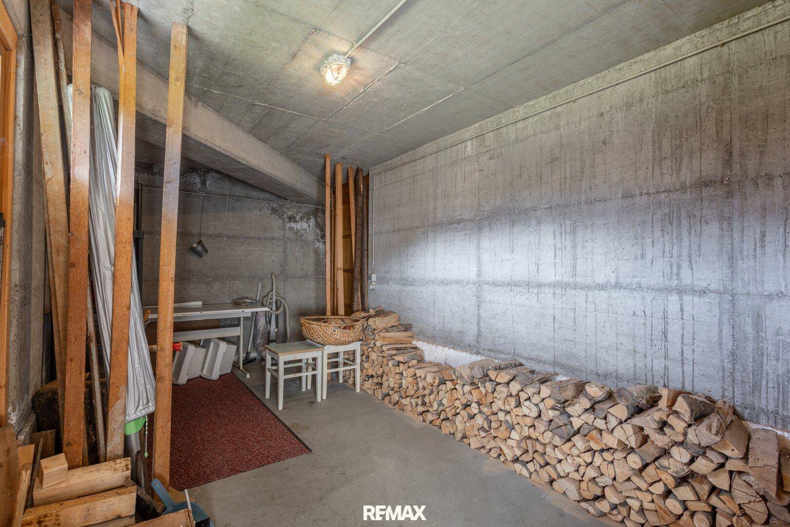 Lagerraum im Keller mit Betonwänden und gestapeltem Brennholz.