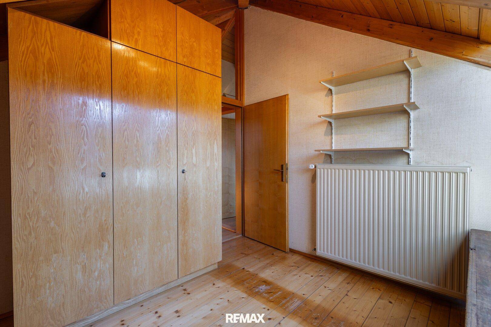 Dachbodenbereich mit Holzboden, Einbauschränken und Heizkörper.