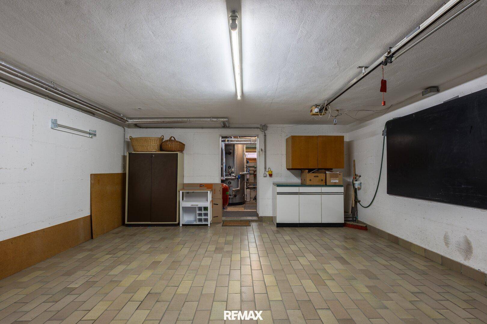 Geräumige Garage mit Fliesenboden, weißen Wänden und Stauraum.