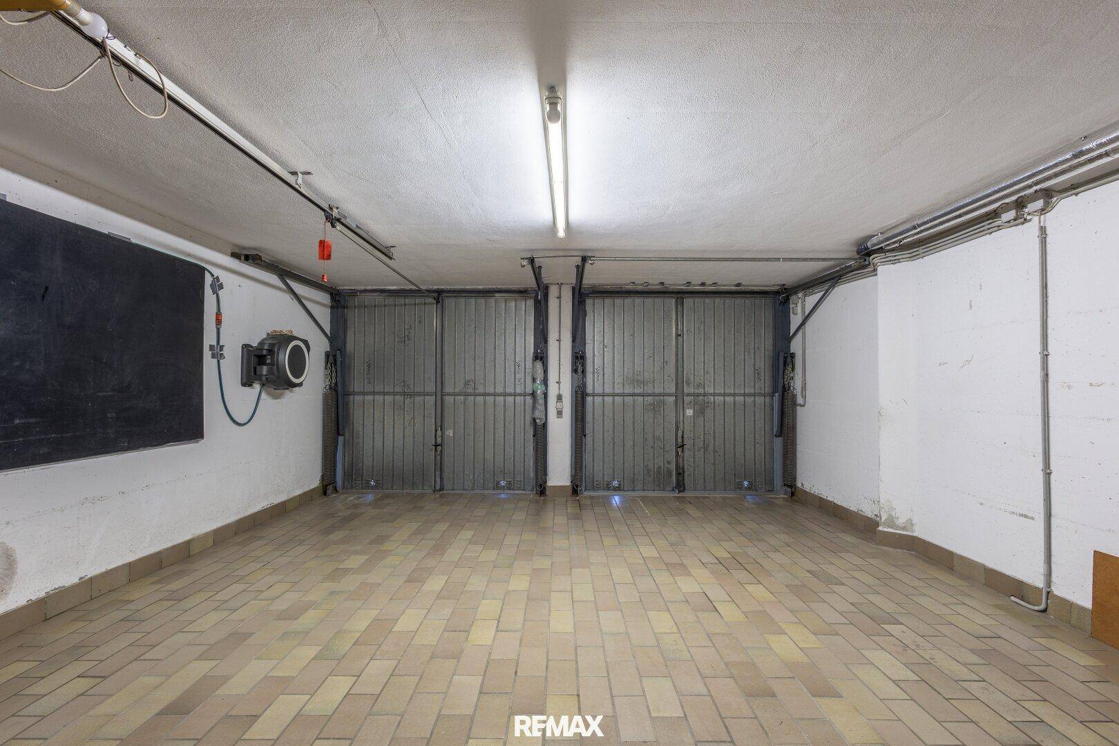 Geräumige Doppelgarage mit Fliesenboden und zwei Garagentoren.
