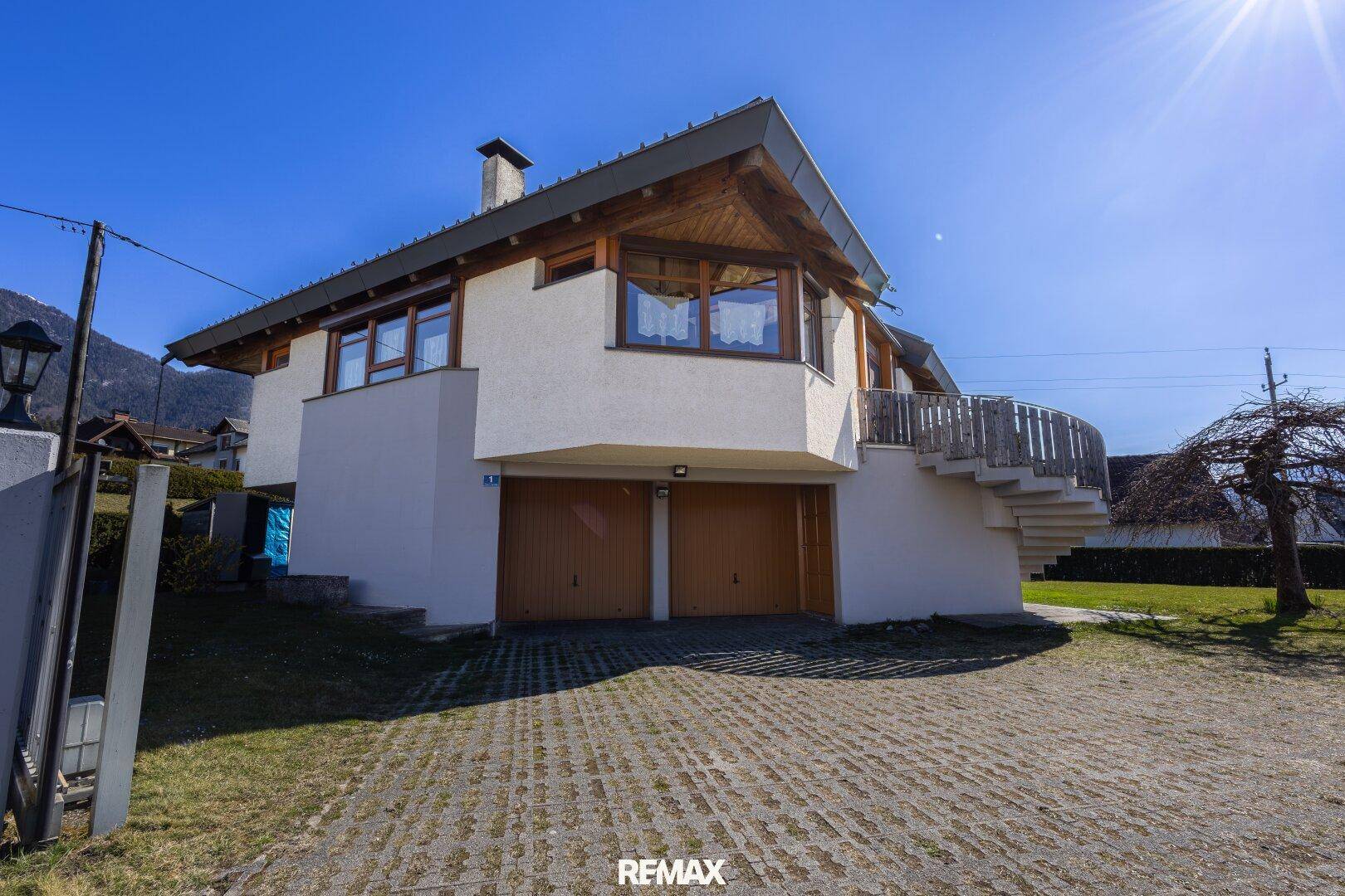 Traditionelles Haus mit Holzgiebel und Doppelgarage in ländlicher Umgebung.