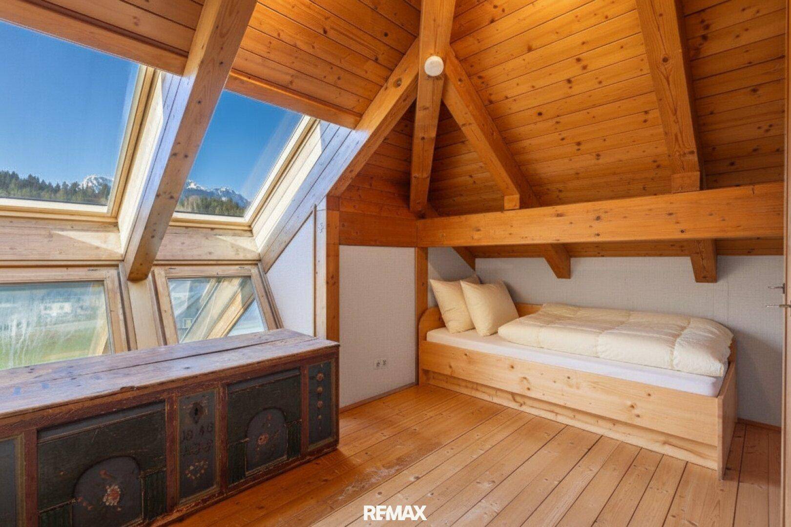 Schlafzimmer im Dachgeschoss mit Holzboden, Dachfenstern und Bergblick.
