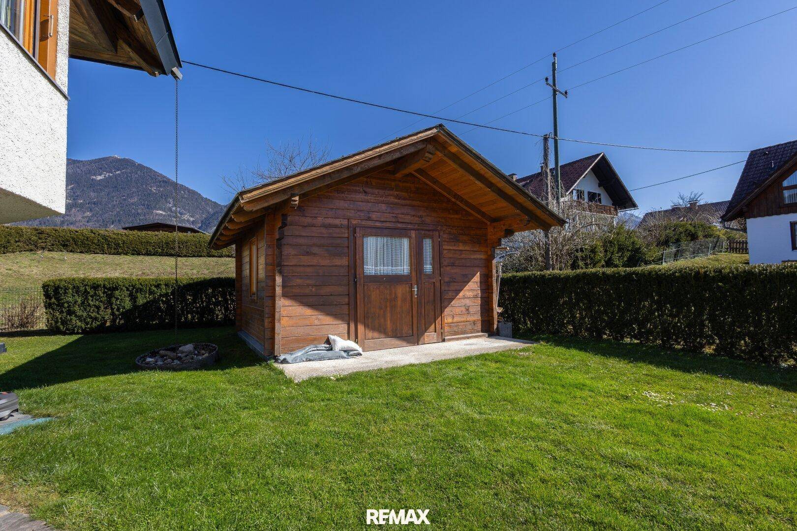 Kleines Holzgartenhaus im Grünen mit Blick auf die Berge.