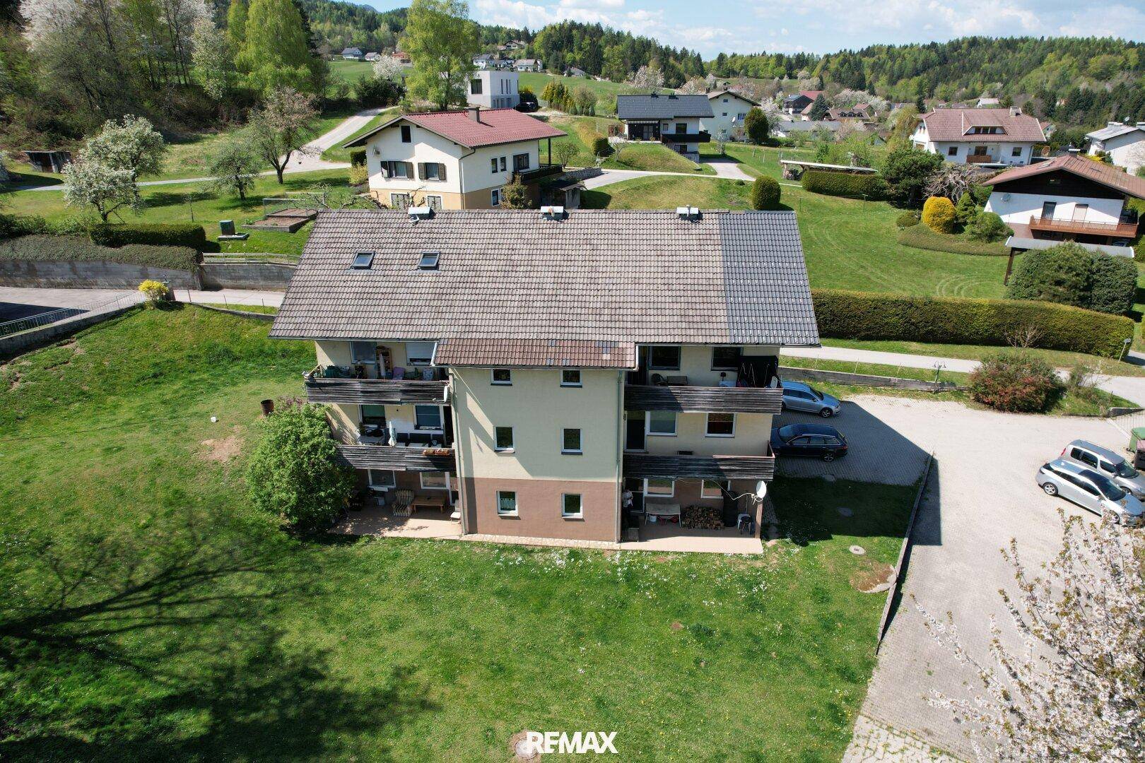 Mehrfamilienhaus in ländlicher Umgebung mit weiteren Häusern und viel Grün.