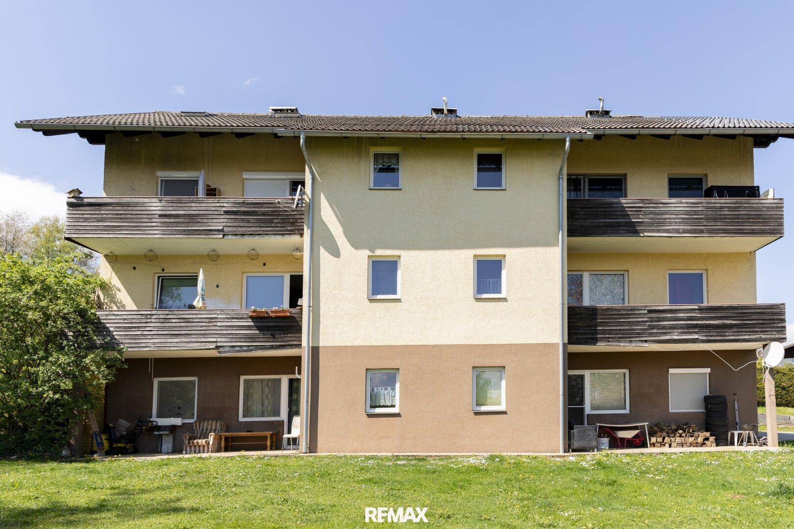 Fassade des Mehrfamilienhauses mit mehreren Balkonen und Fenstern im Erdgeschoss.