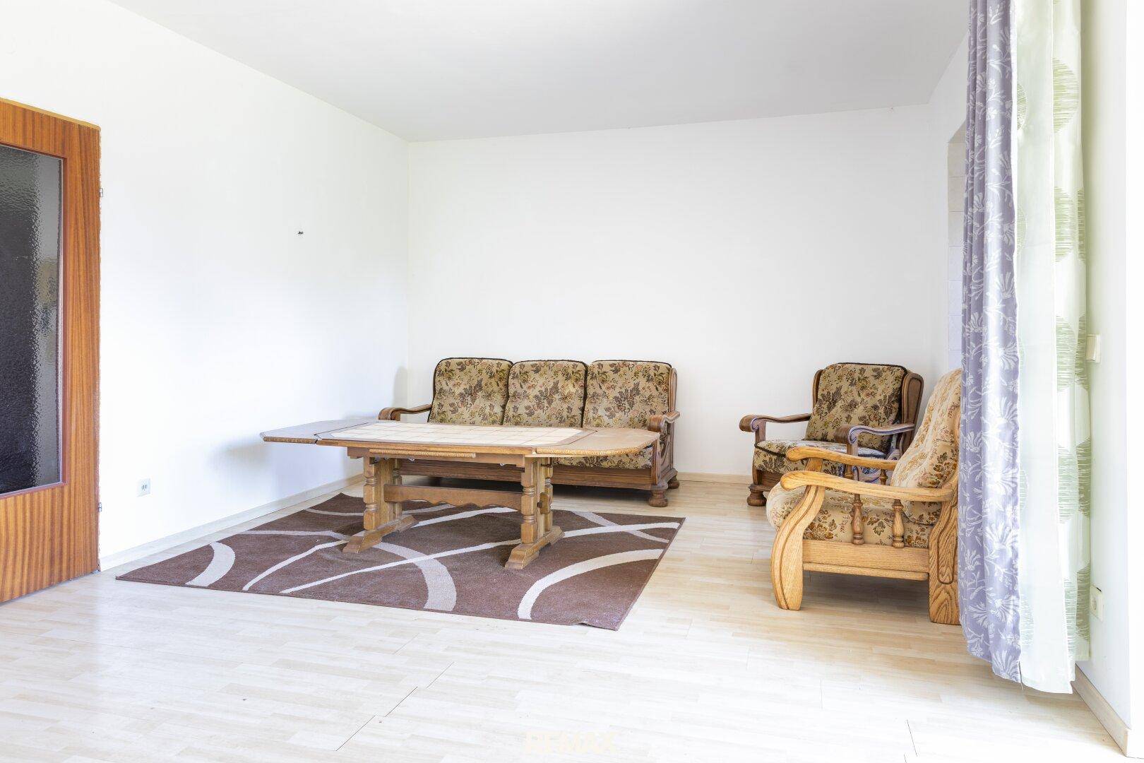 Geräumiges Wohnzimmer mit traditionellen Holzmöbeln und einem gemusterten Teppich.