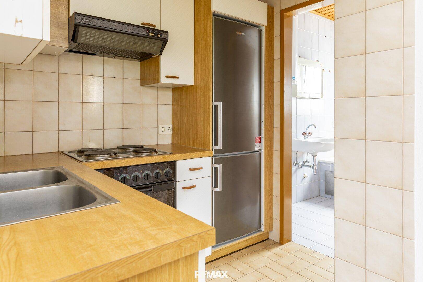 Küche mit integriertem Kühlschrank und direktem Zugang zu einem angrenzenden Badezimmer.