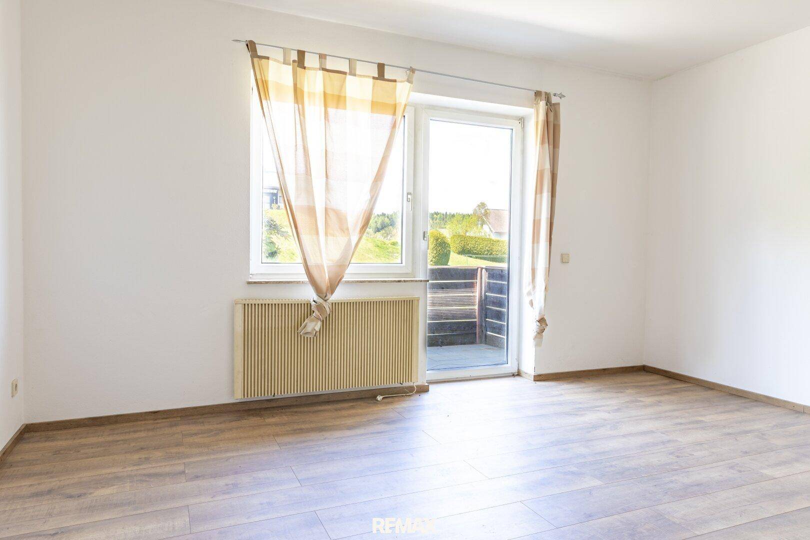 Leerer Raum mit Laminatboden und Zugang zu einem Balkon, ideal für individuelle Gestaltung.