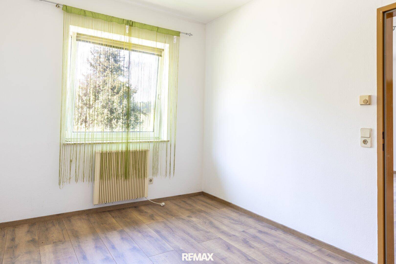 Heller Raum mit Laminatboden und großem Fenster, vielseitig nutzbar.
