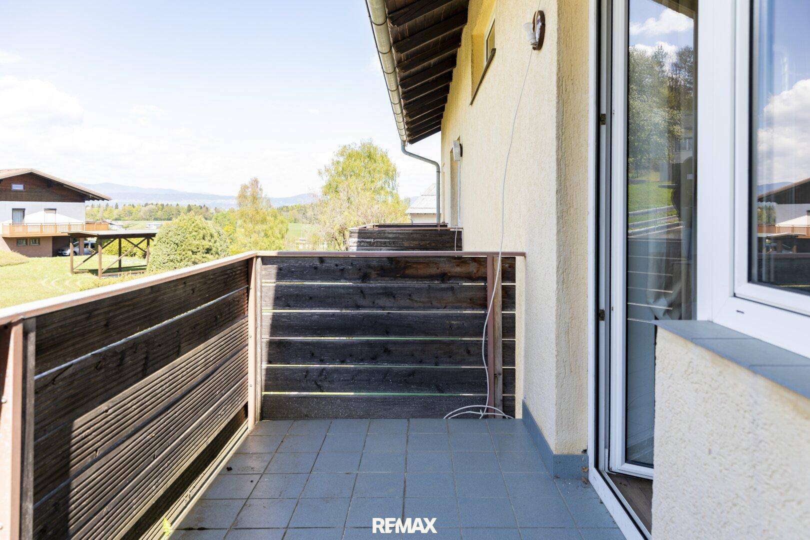 Balkon mit Holzboden und schöner Aussicht auf die umliegende Landschaft und die Berge.