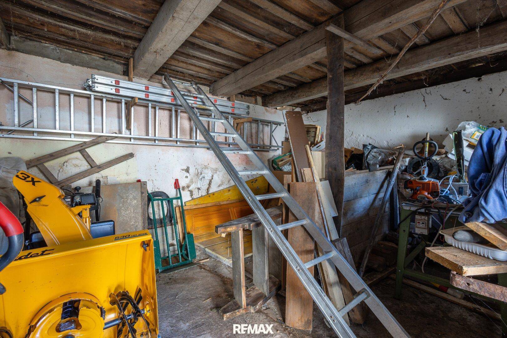 Abstellraum mit Leitern, Werkzeugen und sichtbaren Holzbalken an der Decke.