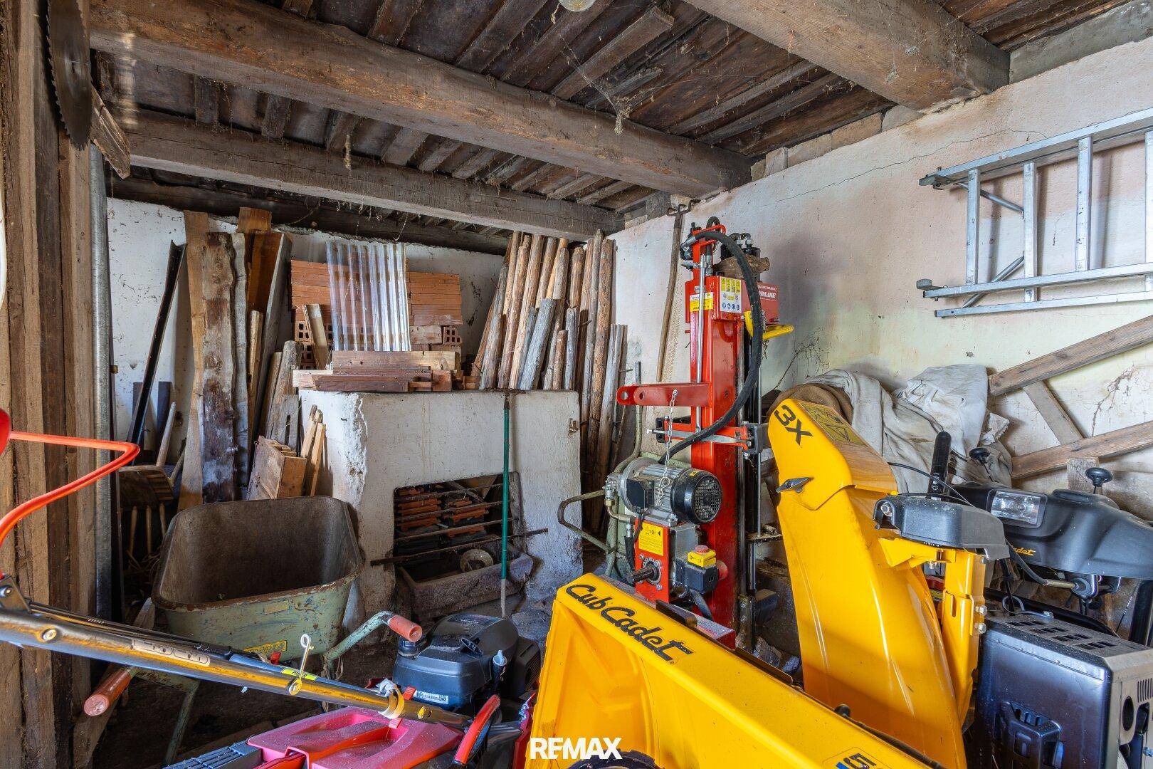Geräumiger Abstellraum mit verschiedenen Geräten, Werkzeugen und Holzbalkendecke.