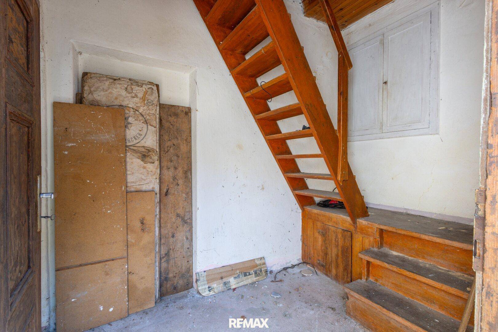 Eingangsbereich mit Holztreppe und Abstellmöglichkeiten unter der Treppe.