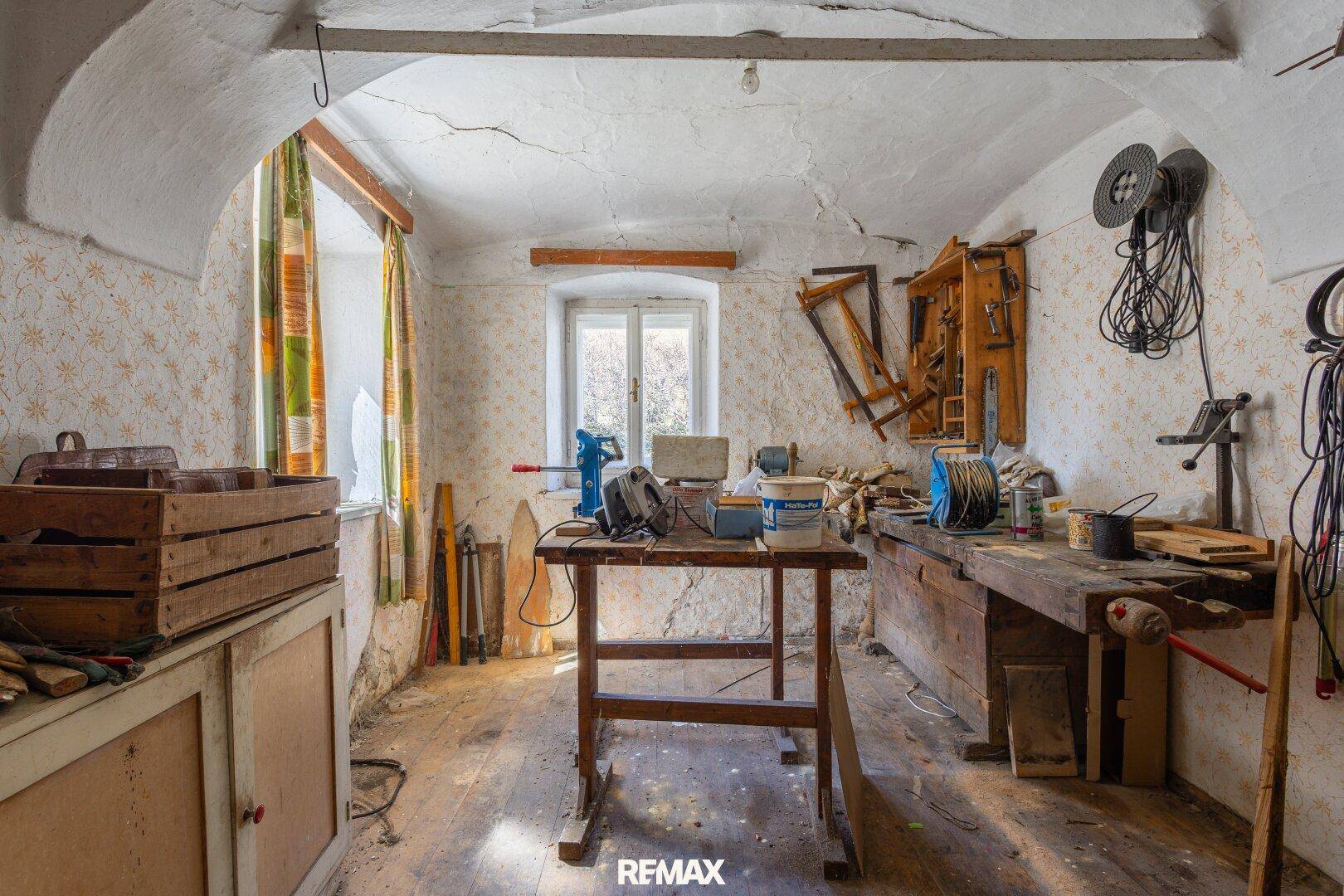 Werkstatt mit Werkbänken, Werkzeugen und gewölbter Decke, ideal für handwerkliche Arbeiten.