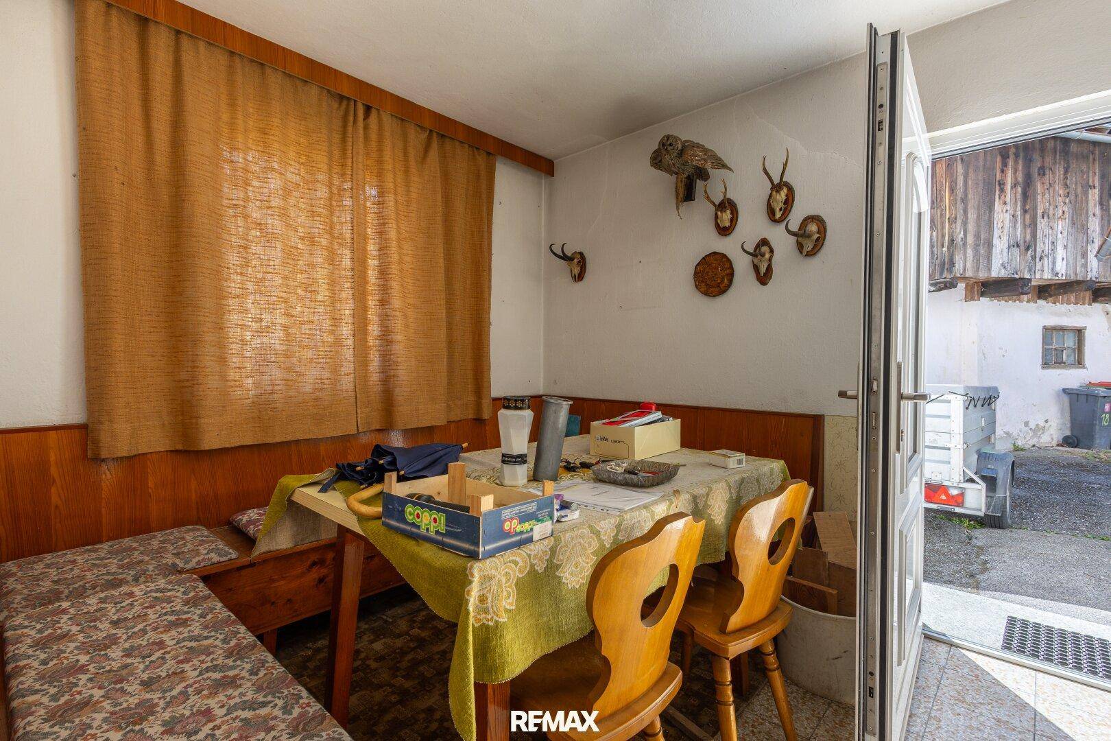 Gemütlicher Essbereich mit Holztisch, Bänken und traditioneller Hirschgeweih-Dekoration.