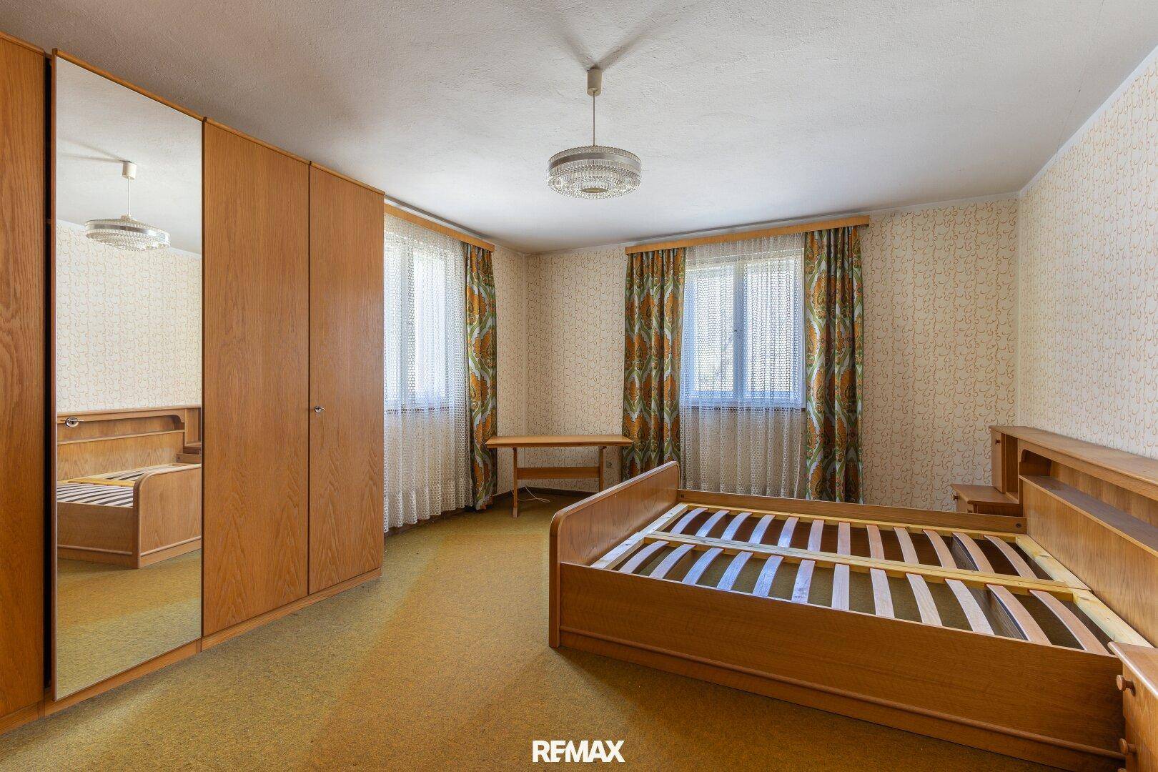 Schlafzimmer mit Doppelbett, Spiegelschrank und Teppichboden in hellem Ambiente.