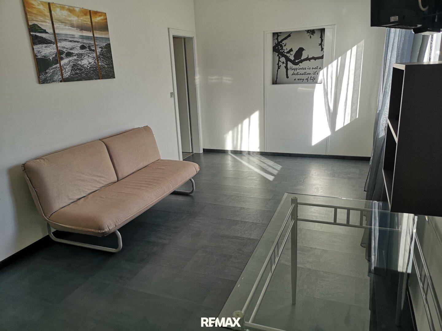 Heller Wohnbereich mit Sofa und Laminatboden.