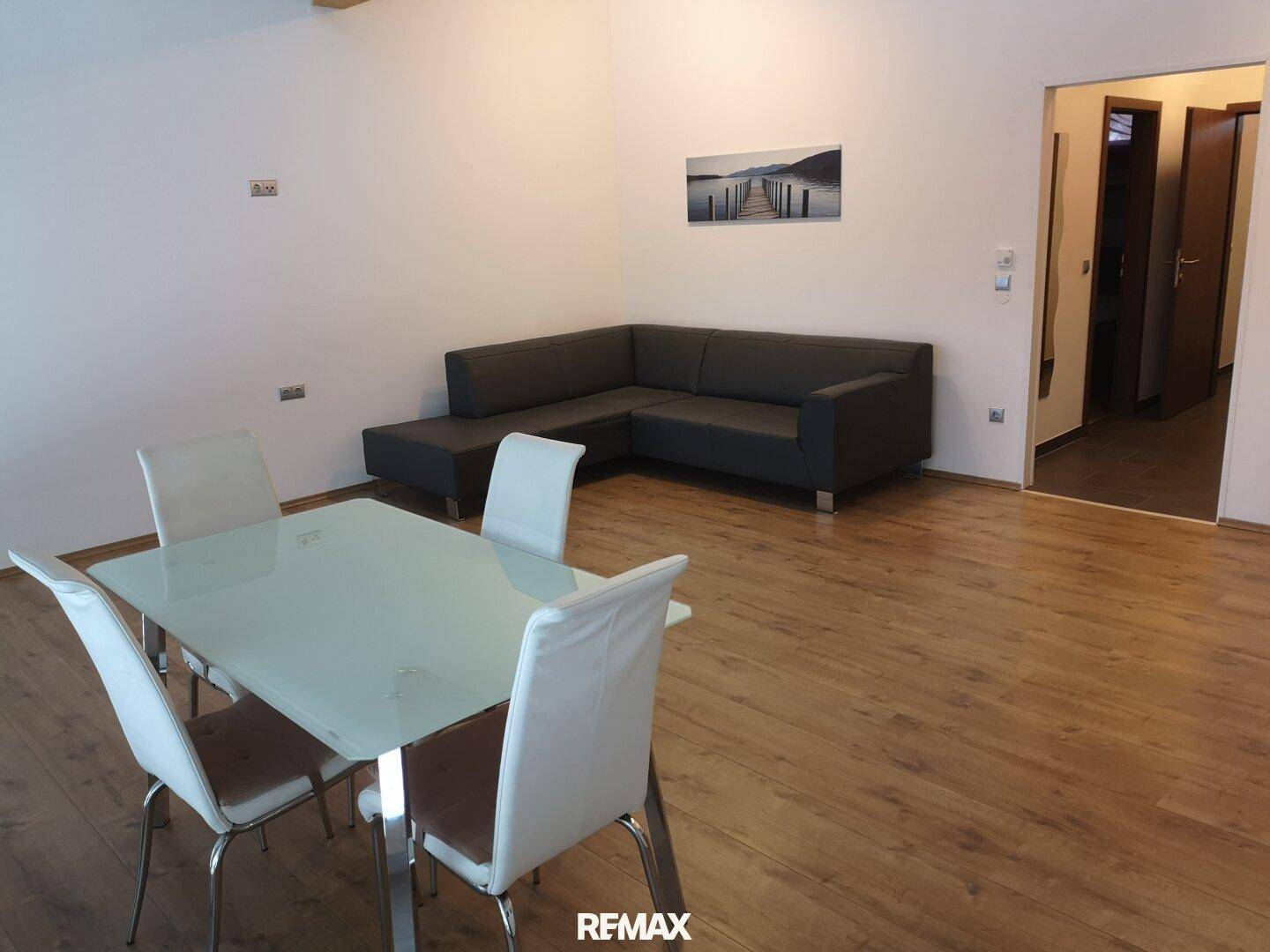 Offener Wohn-Essbereich mit Sofa, Esstisch und Laminatboden.