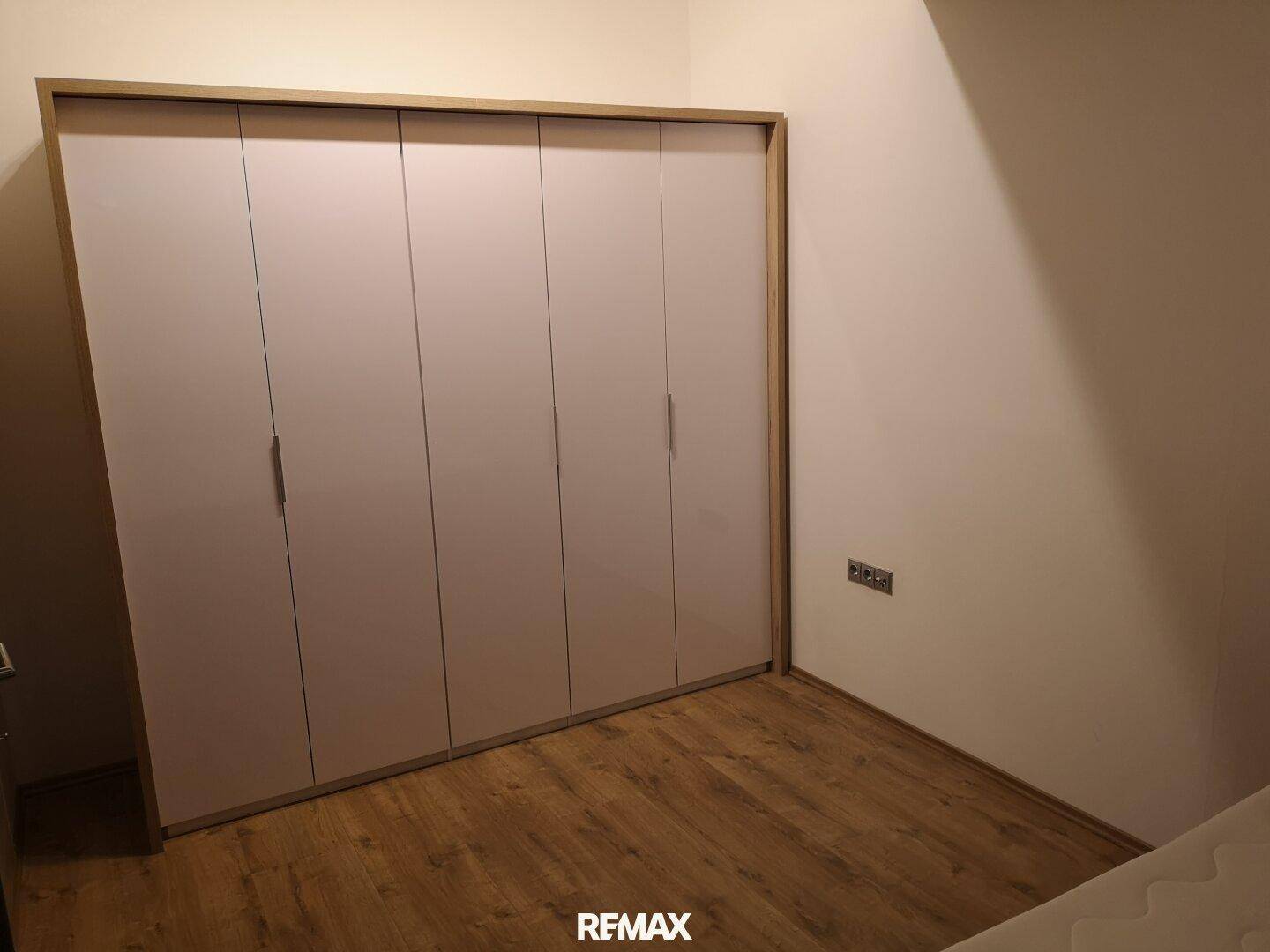 Schlafzimmer mit großem Einbauschrank und Laminatboden.