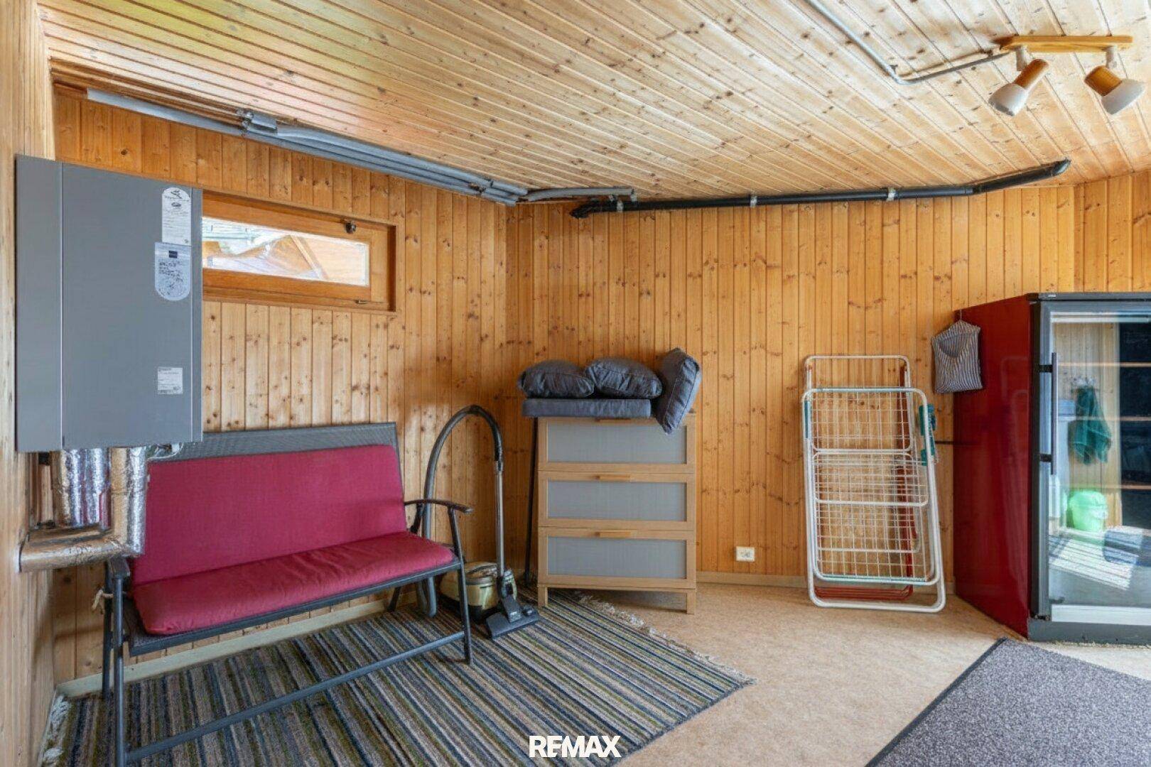 Hauswirtschaftsraum mit Holzvertäfelung, Sitzbank und Wäscheständer.