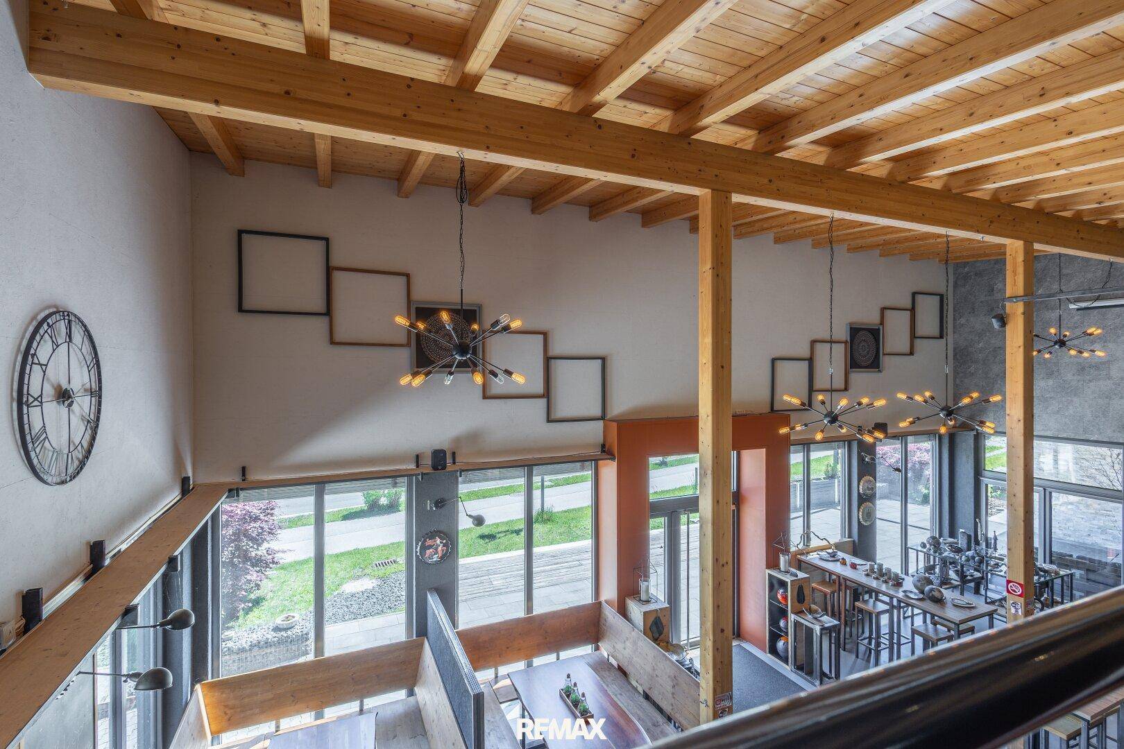 Blick von oben auf den weitläufigen Wohnbereich mit hohen Decken und modernen Leuchten.